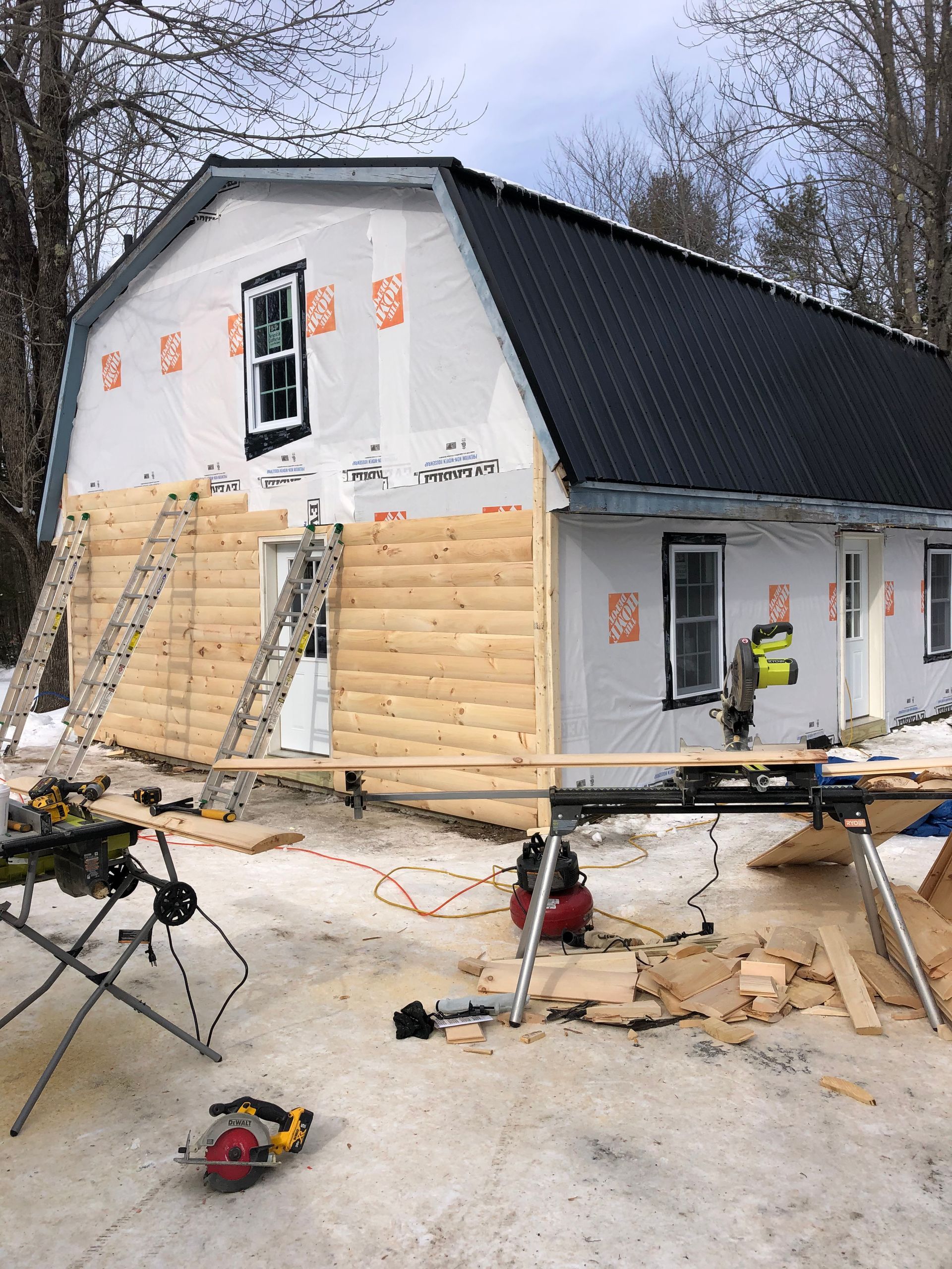 A house is being built with a log siding and a black roof.
