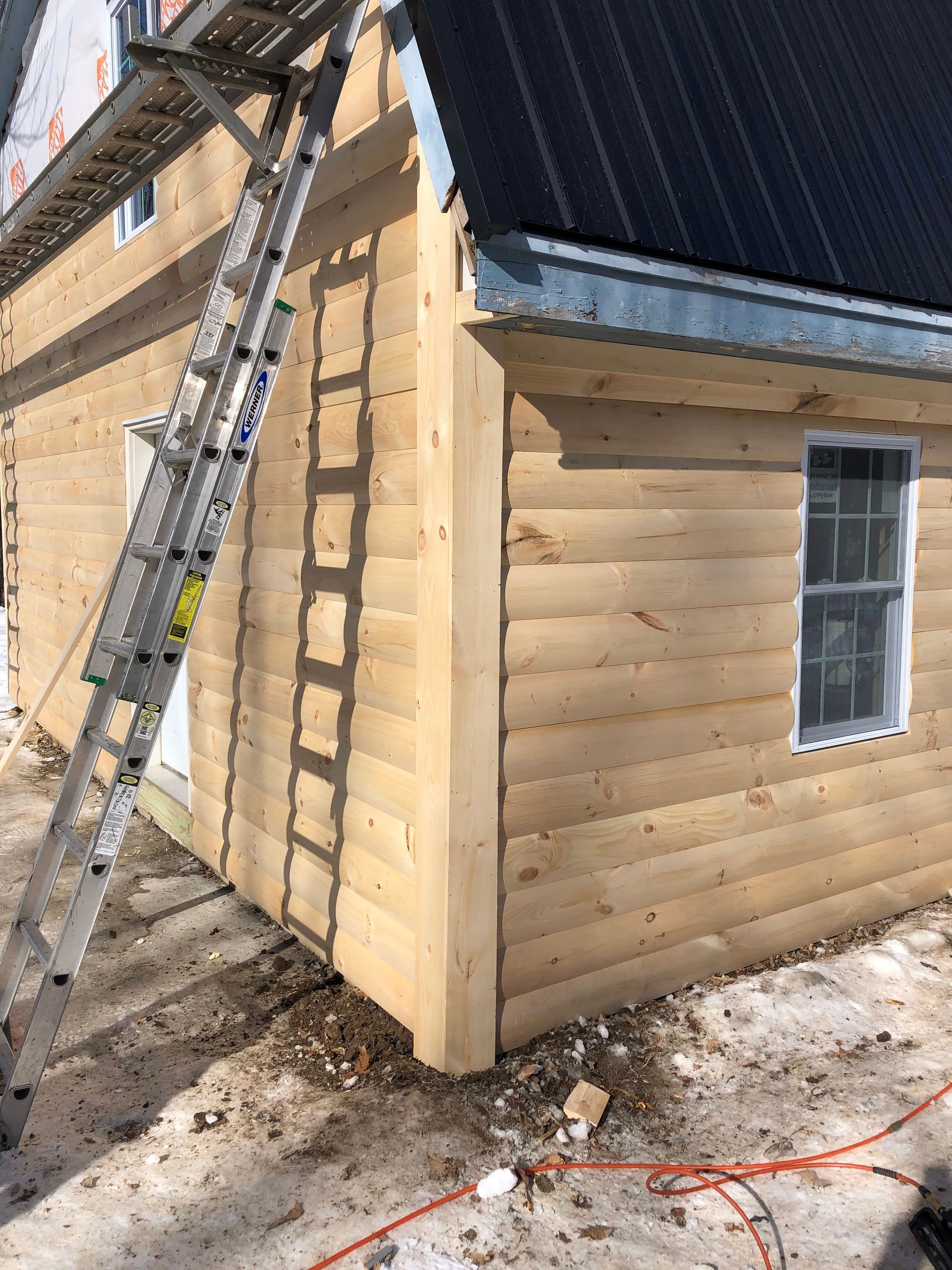 A ladder is sitting on the side of a log cabin.