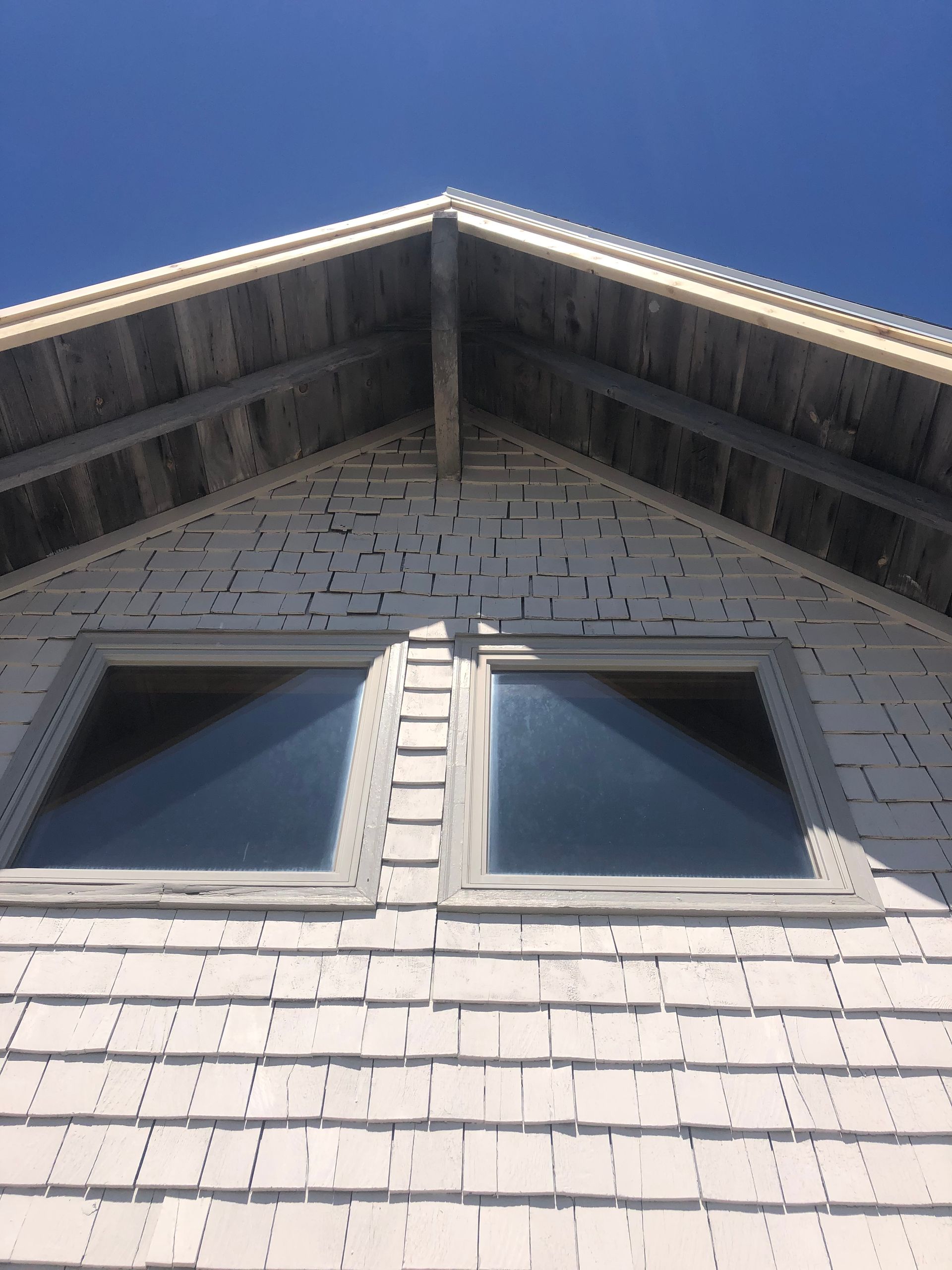 Looking up at the roof of a house with two windows