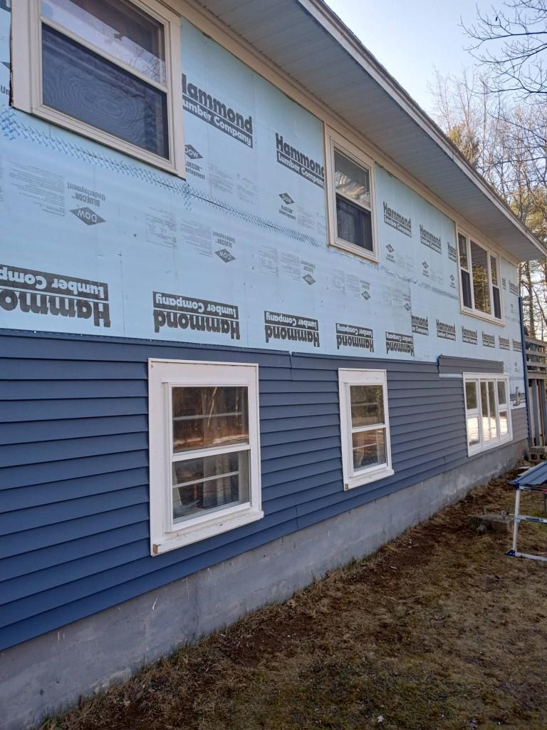 A house with blue siding and white windows is being remodeled.