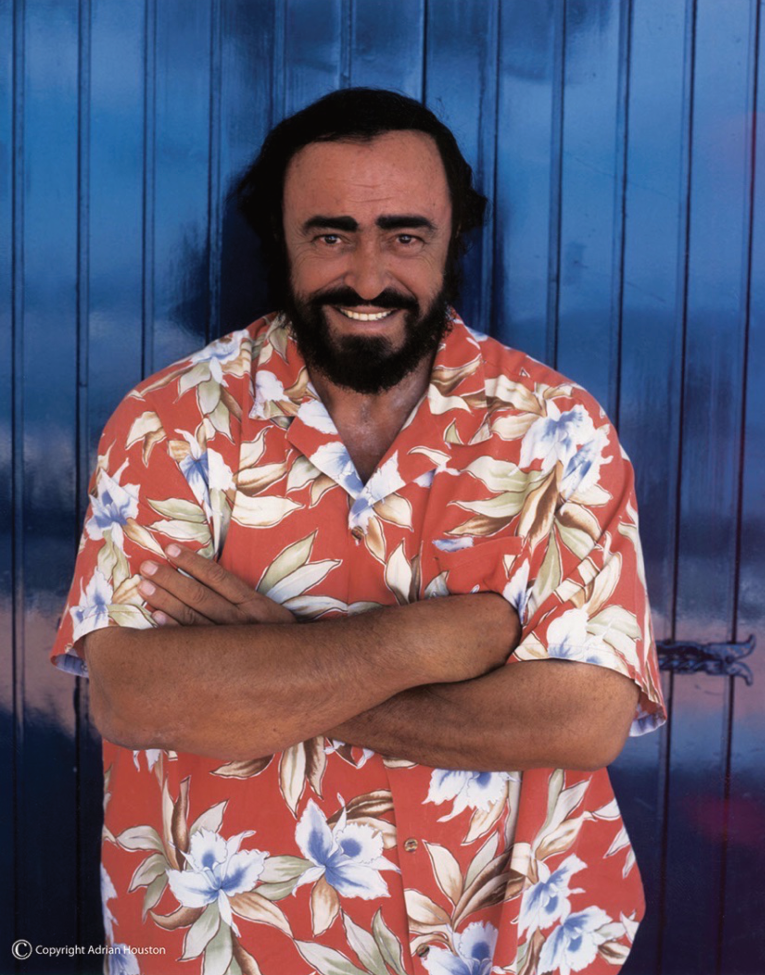 A man with a beard wearing a hawaiian shirt with his arms crossed