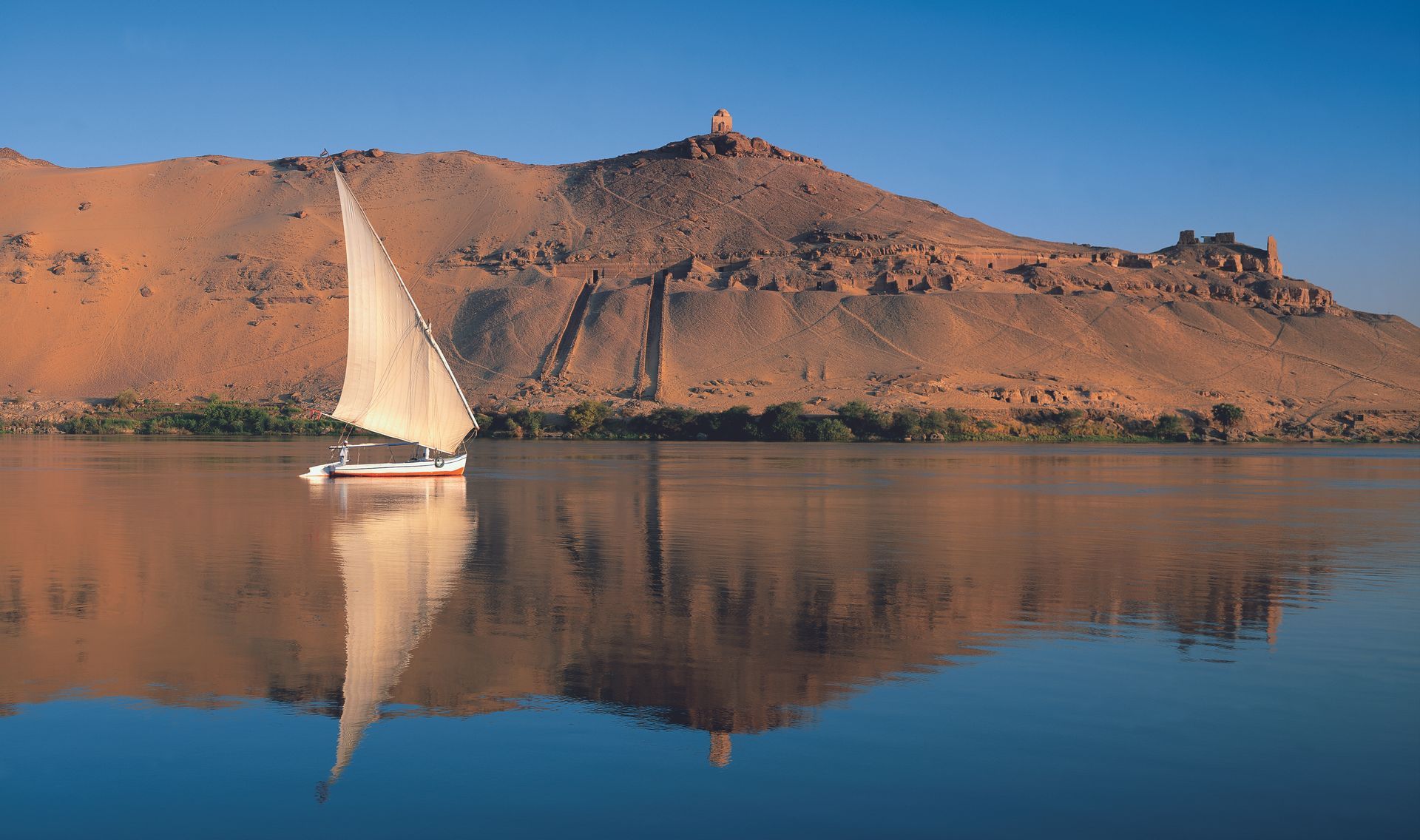 A sailboat is floating on a lake with mountains in the background.