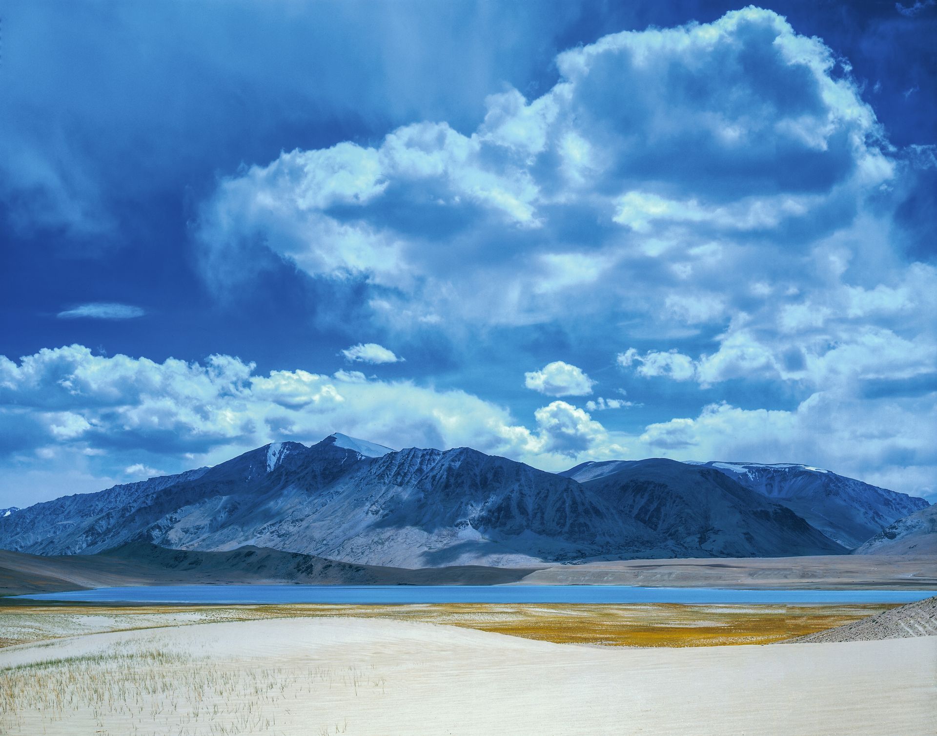 A lake with mountains in the background and clouds in the sky