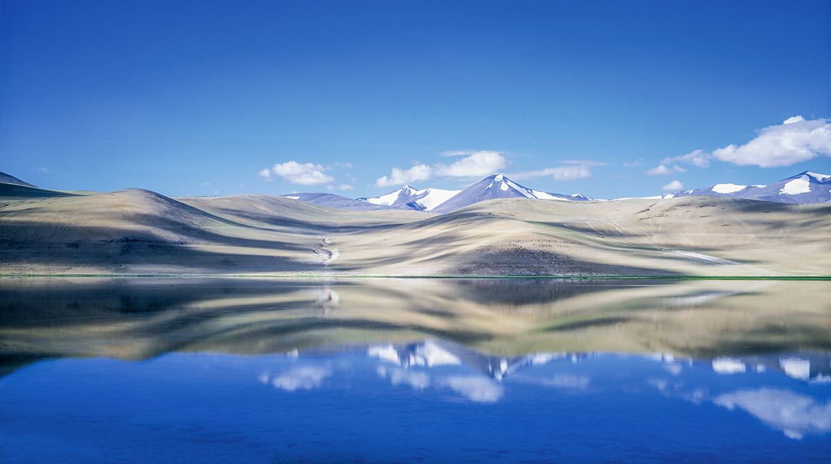 A lake with mountains in the background and mountains reflected in the water.