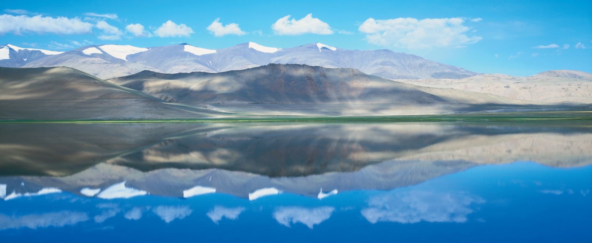 A lake with mountains in the background and mountains reflected in the water.