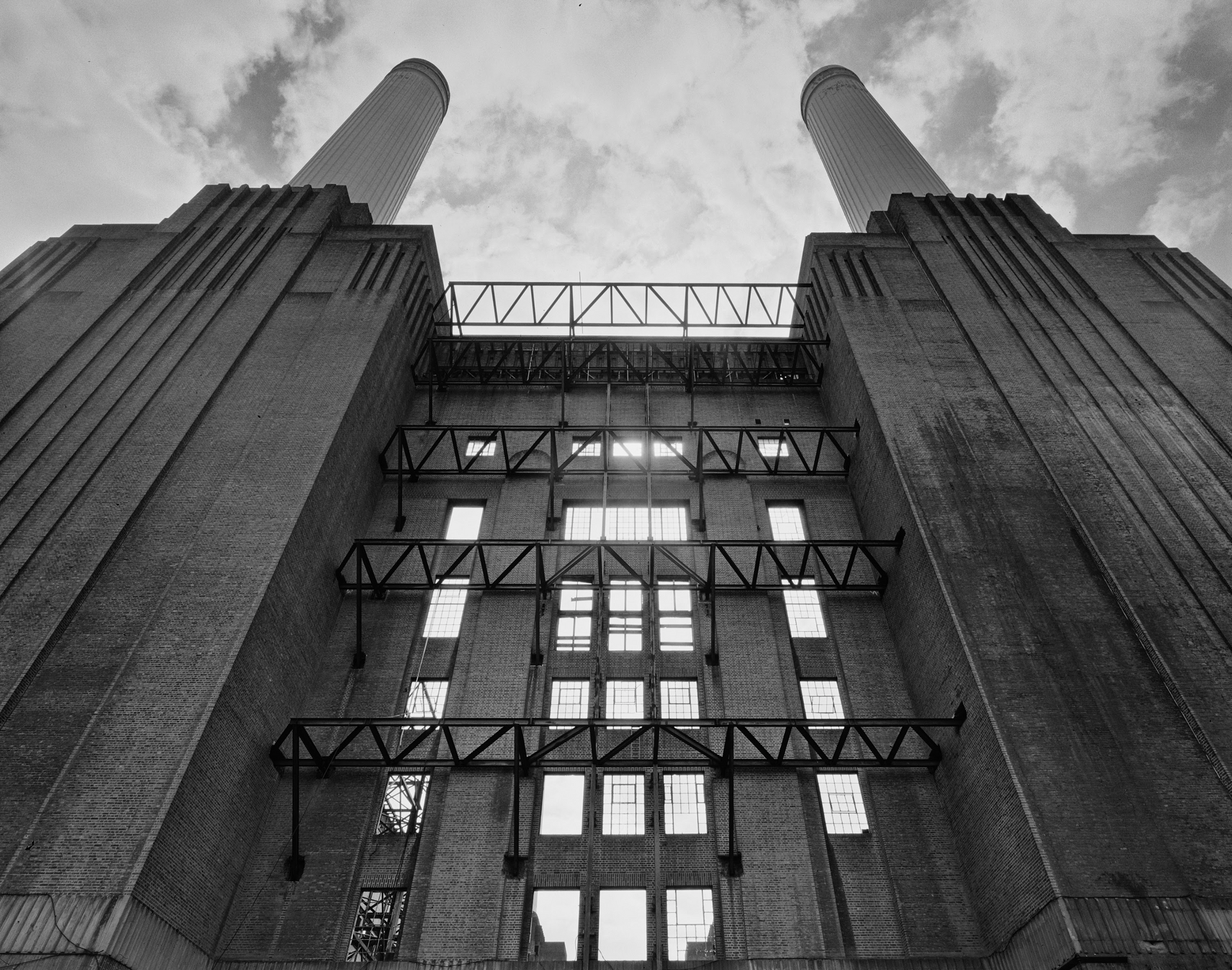 A black and white photo of a large brick building with two chimneys