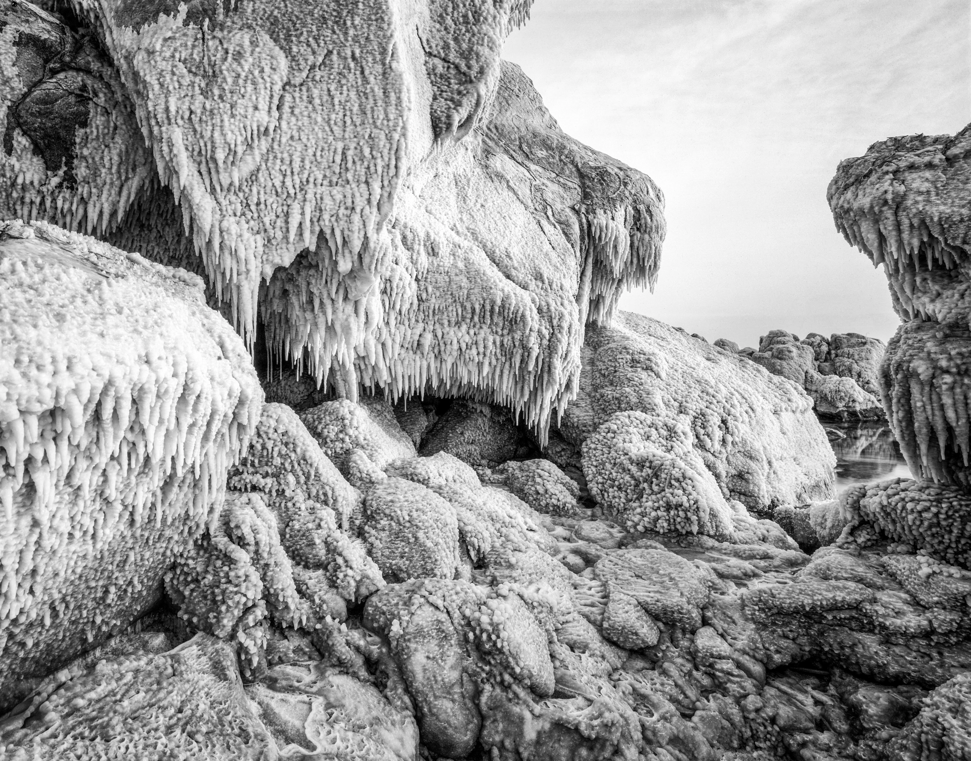 A black and white photo of a rock formation covered in ice.