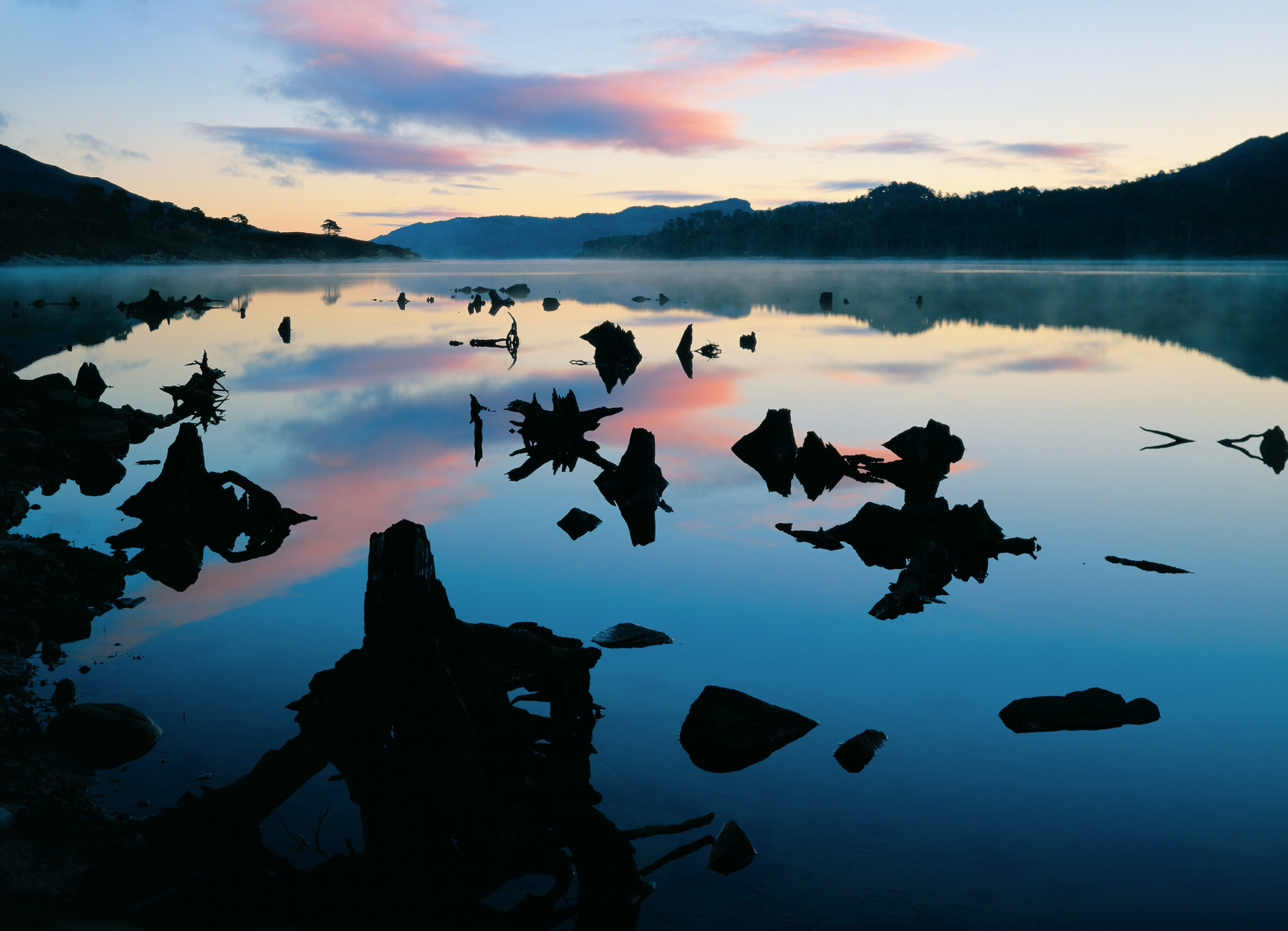 A sunset over a lake with rocks in the water