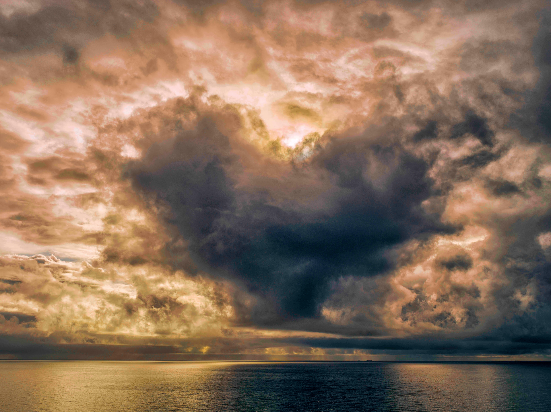 The sun is shining through the clouds over the ocean.