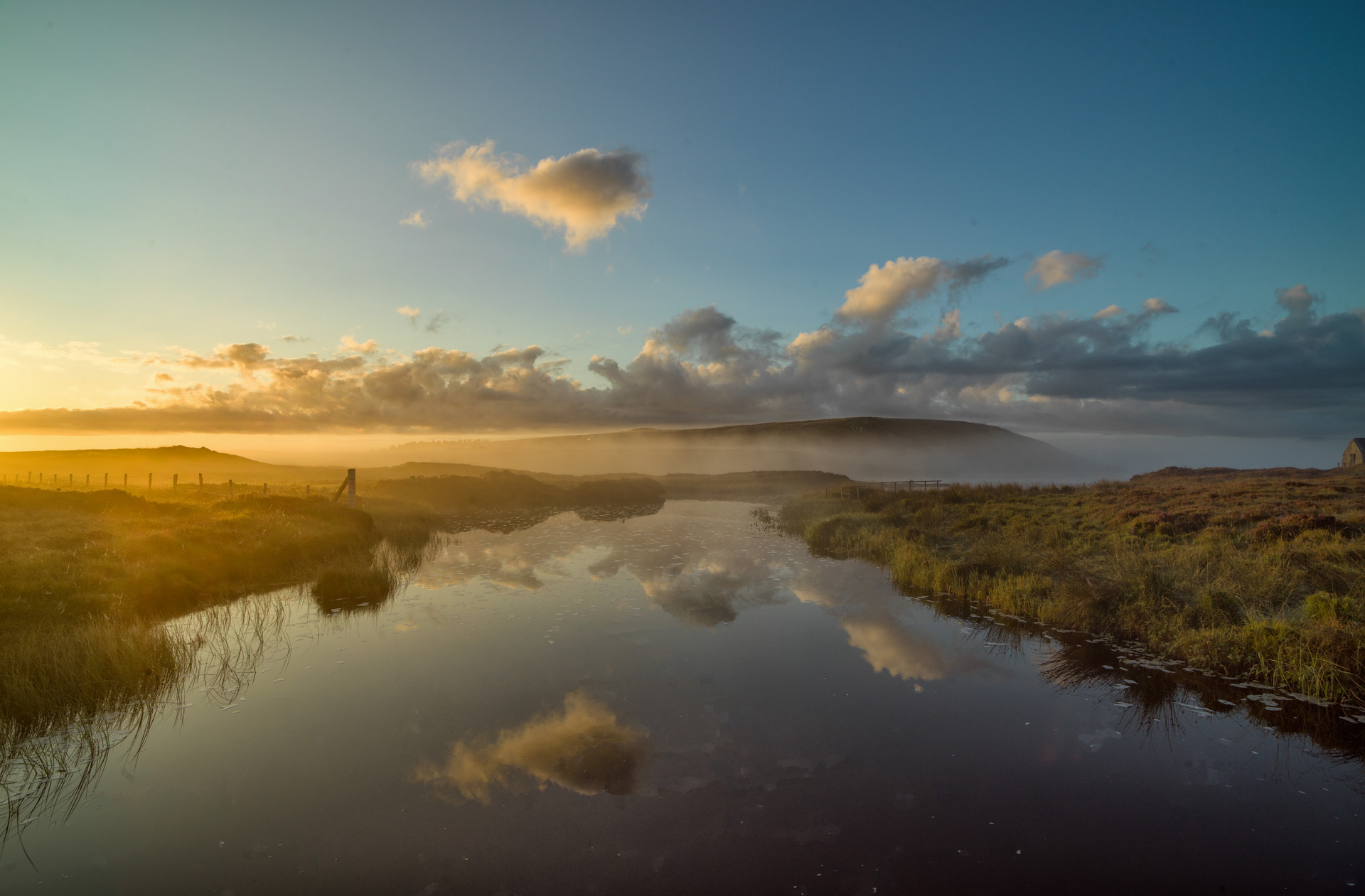 A river with a sunset in the background and clouds reflected in the water.