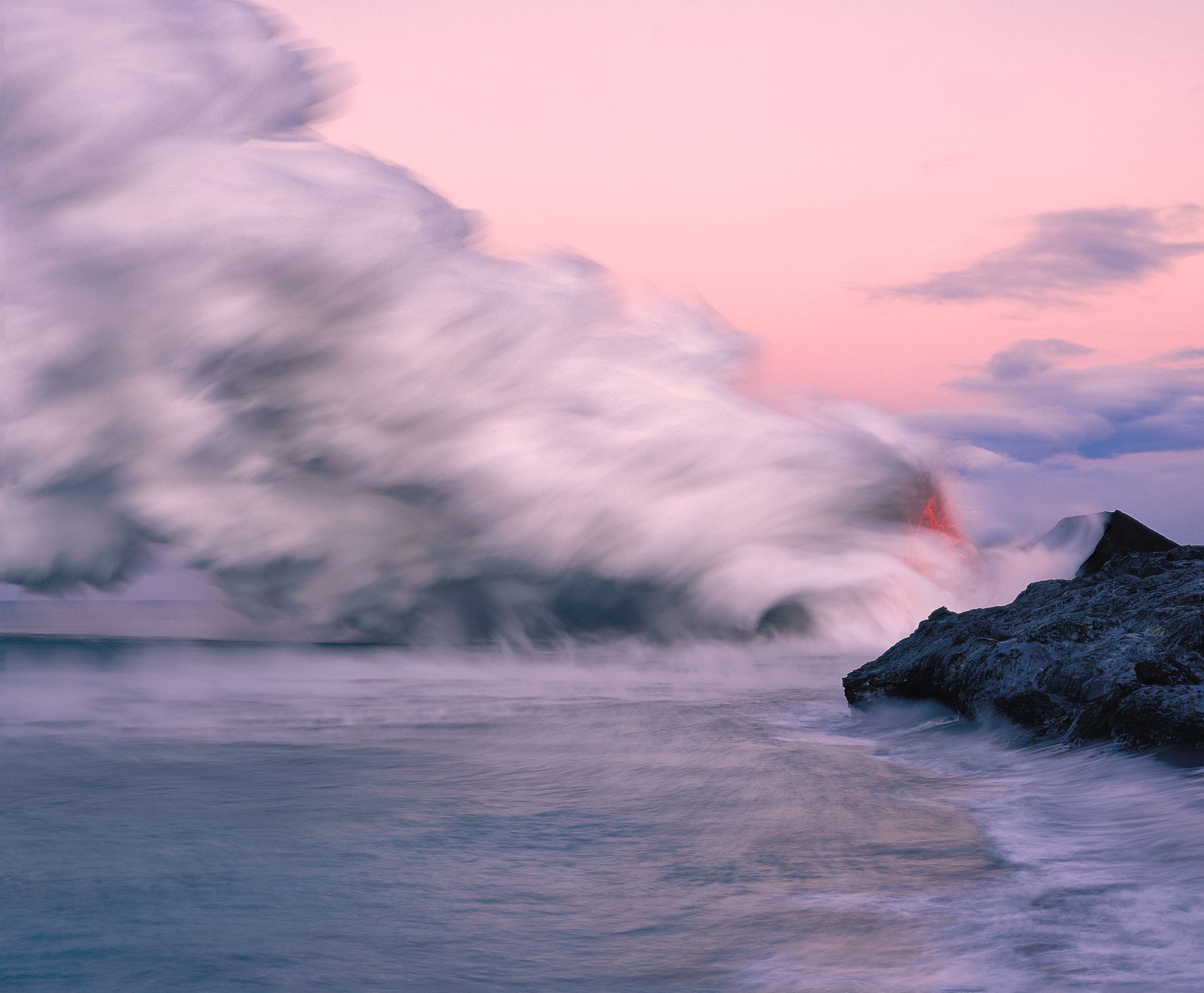 A volcano is erupting into the ocean at sunset