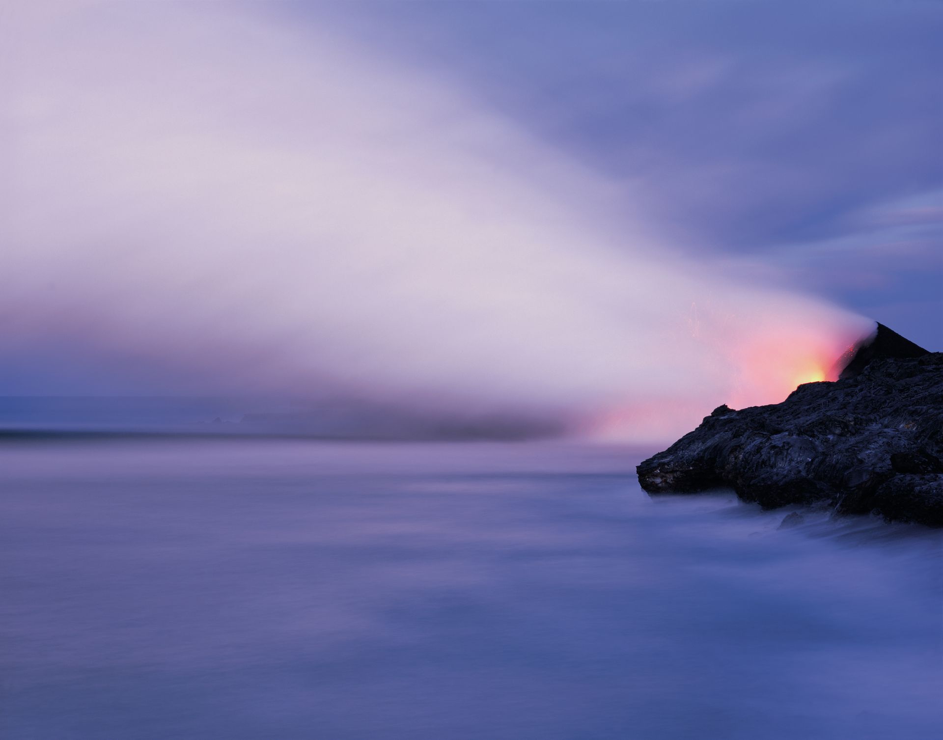 A lighthouse is lit up in the distance over a body of water