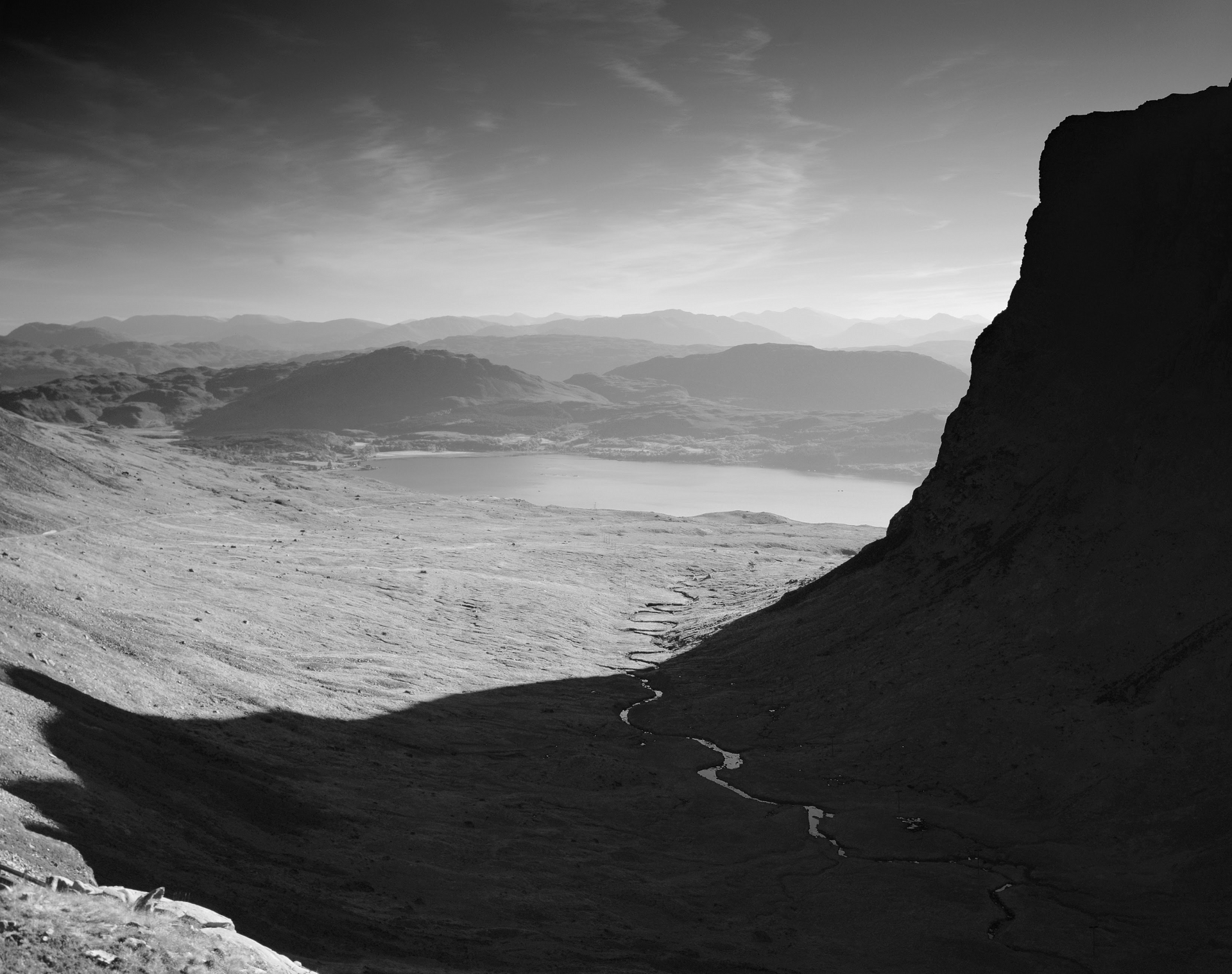 A black and white photo of a valley with mountains in the background