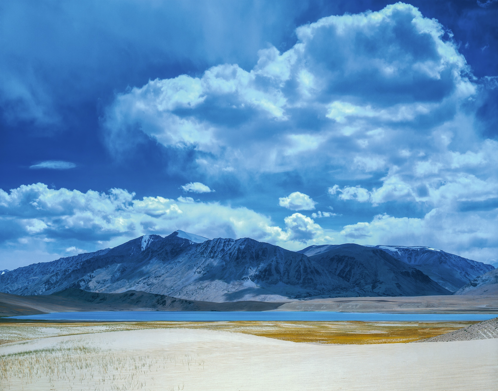 A lake with mountains in the background and clouds in the sky