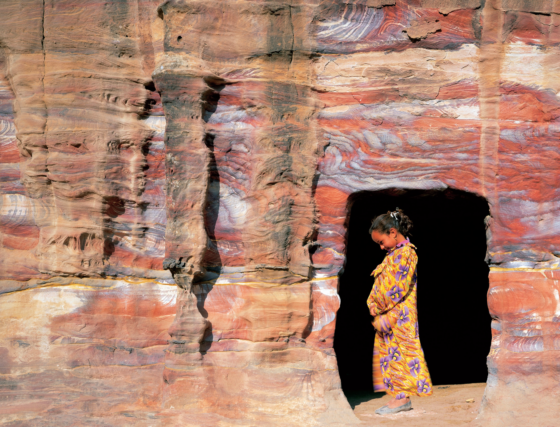 A girl in a yellow dress is standing in a cave
