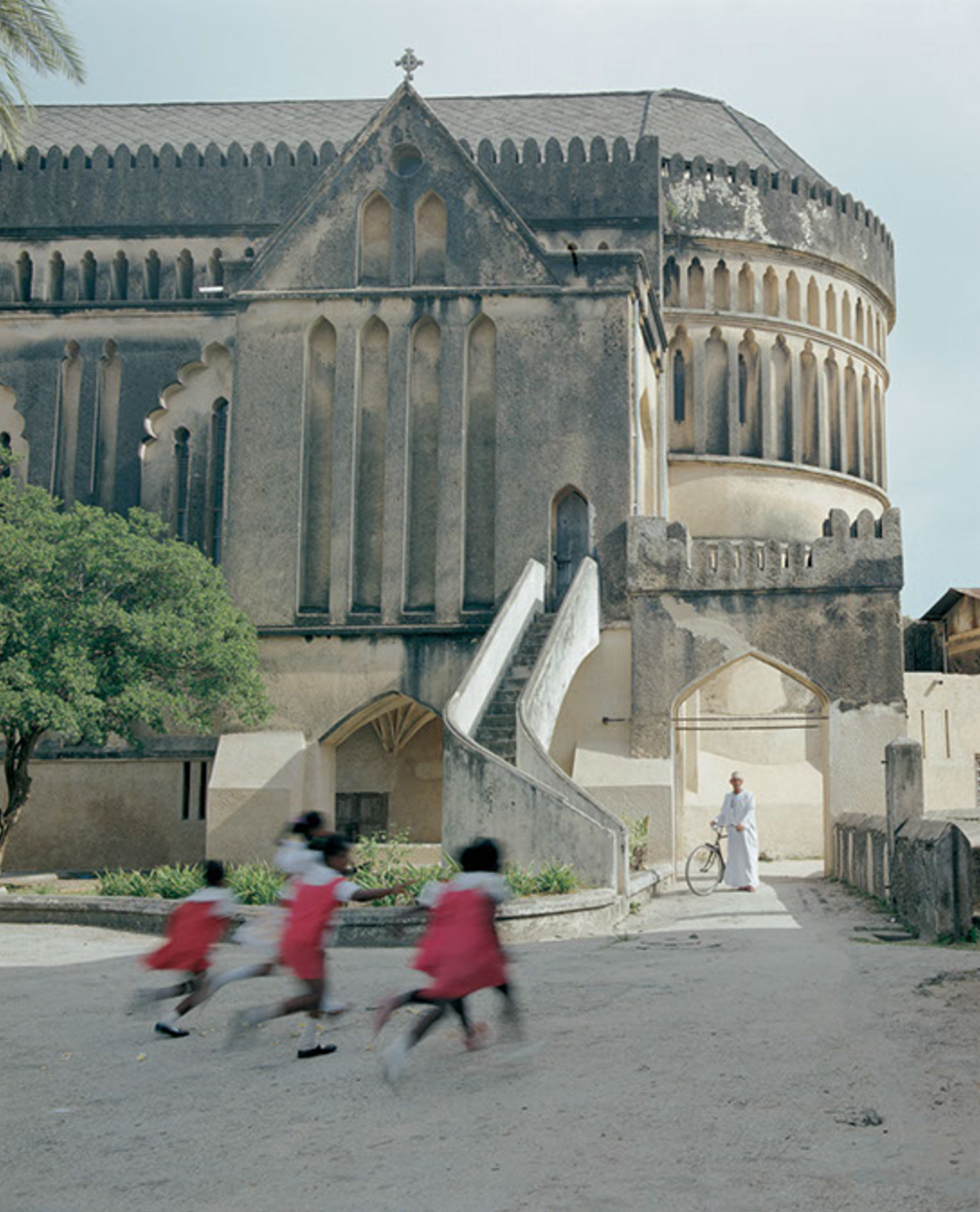 A group of children are running in front of a large building