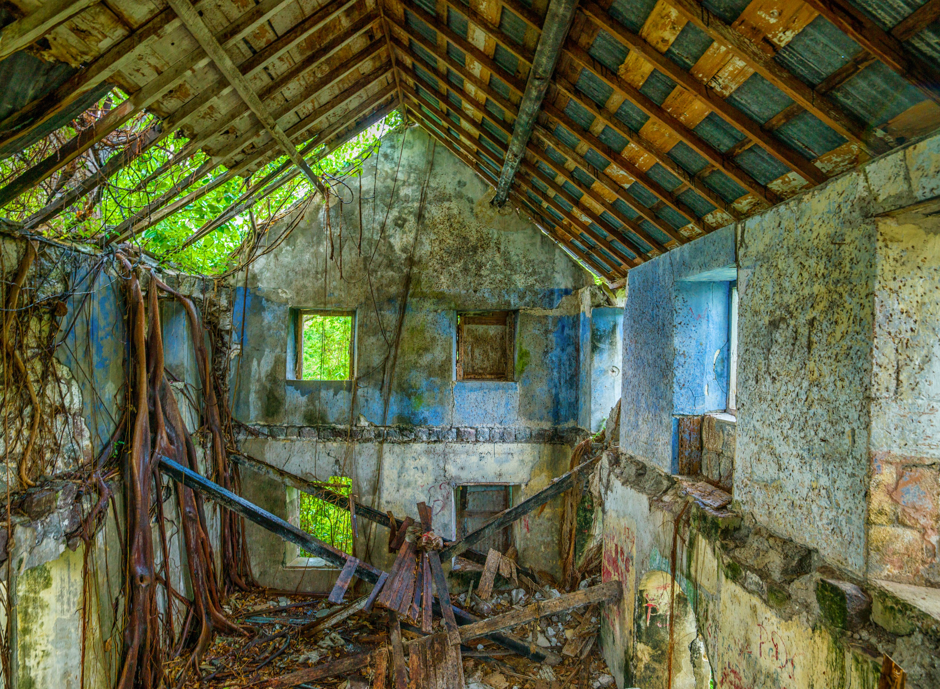 The inside of an abandoned building with a wooden roof.