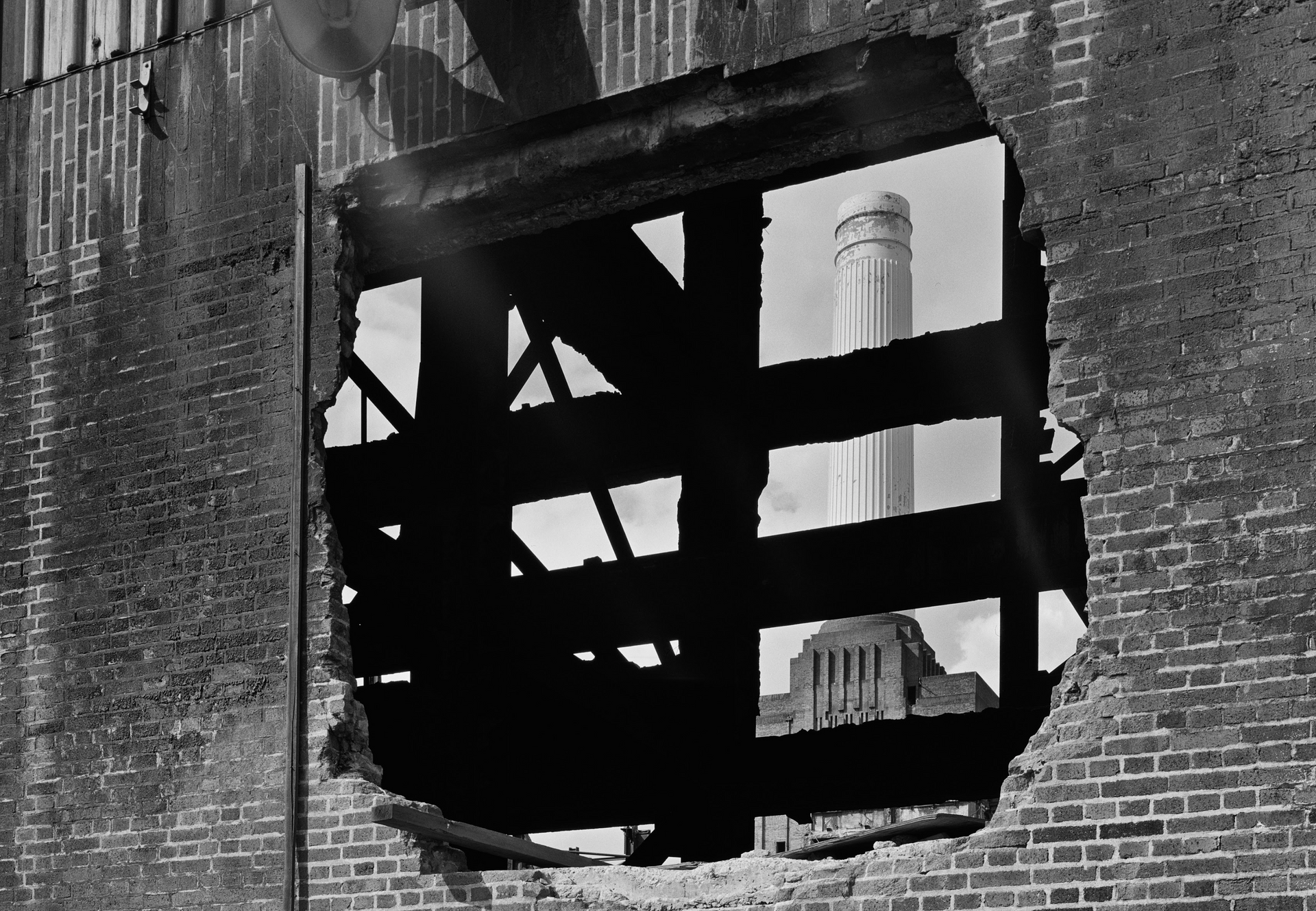 A black and white photo of a brick building with a hole in it