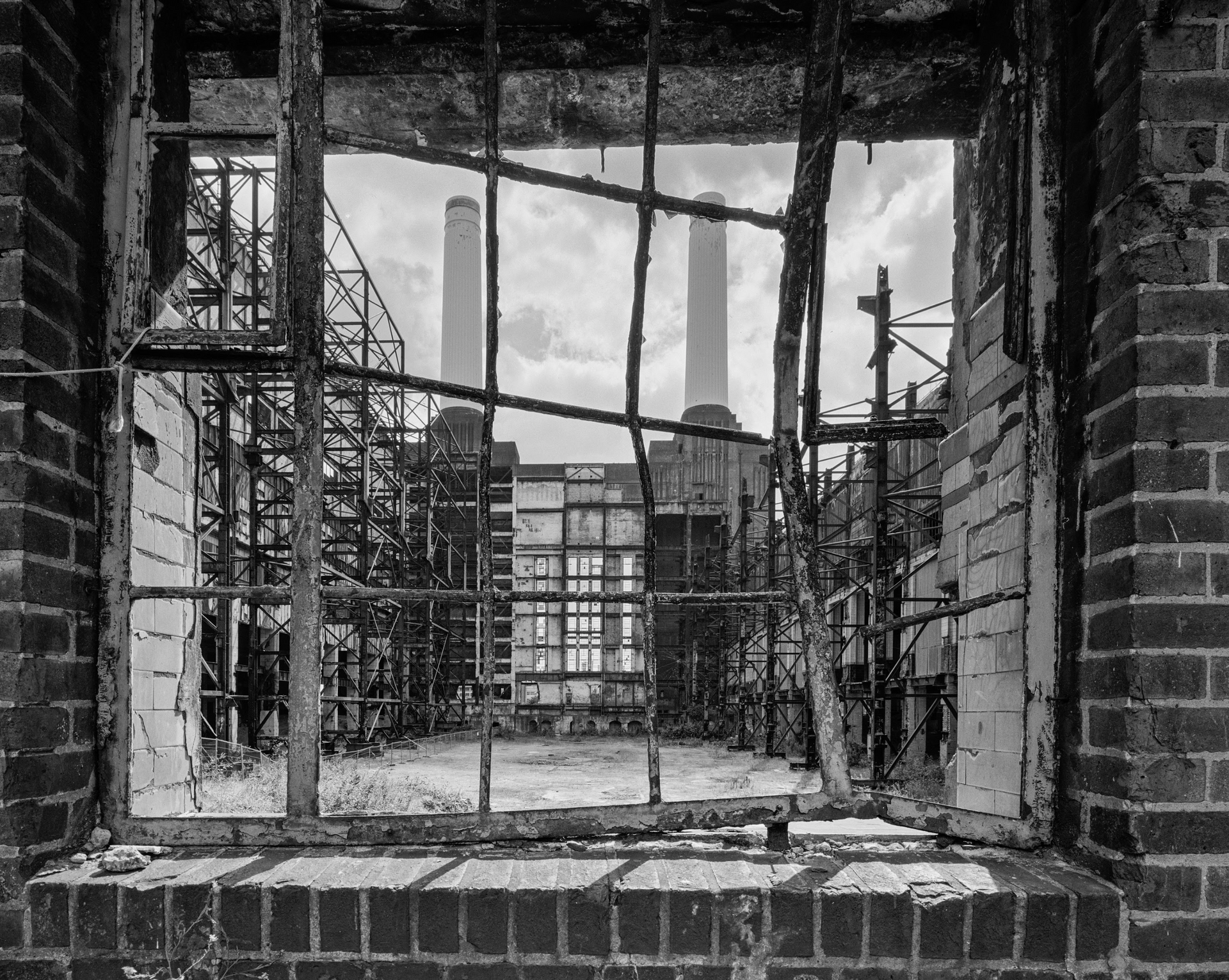 A black and white photo of an abandoned factory through a window.