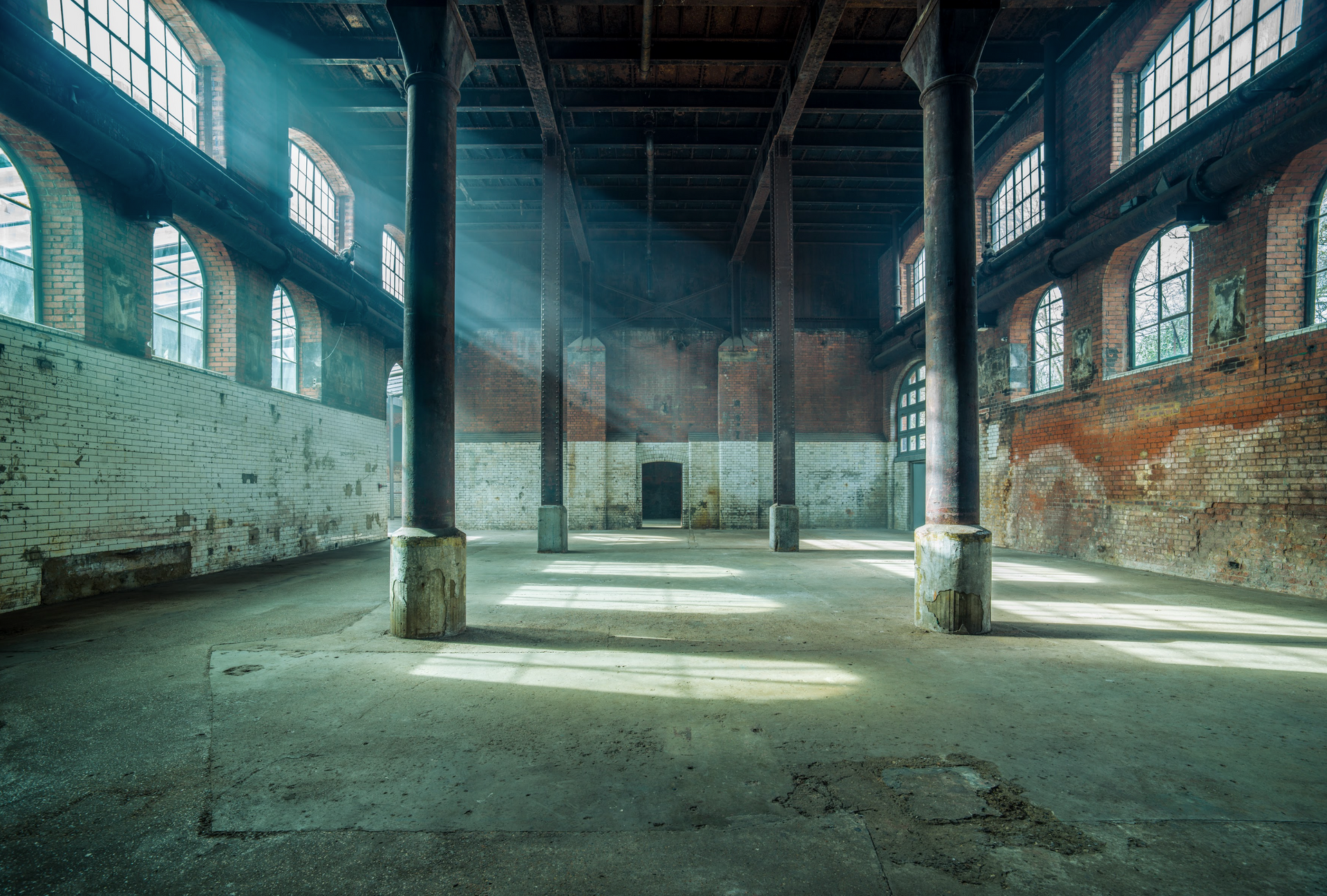 A large empty warehouse with a lot of windows and columns.
