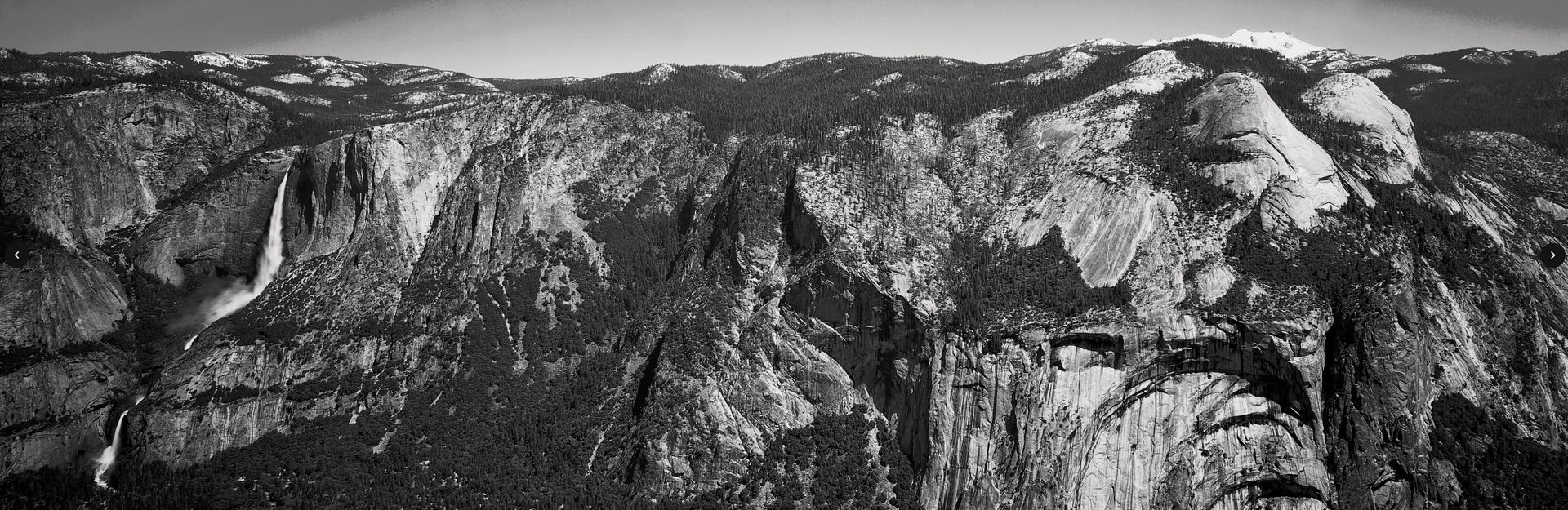A black and white photo of a mountain covered in trees.