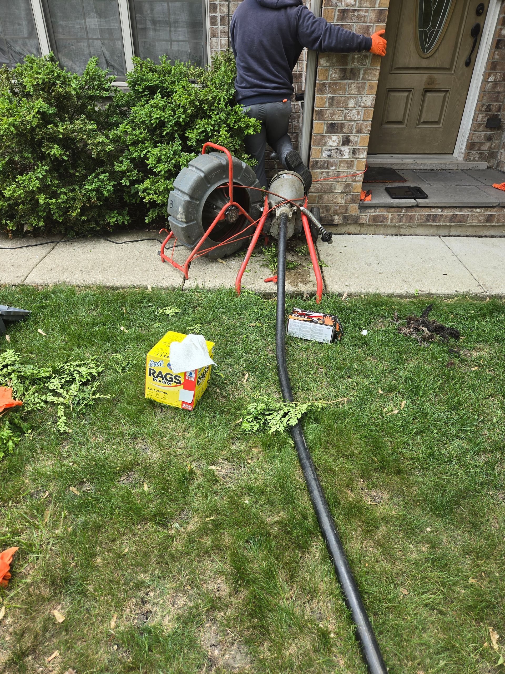 MDM Plumbing & Sewer LLC | A man is working on a drain in front of a house.