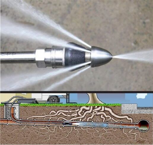 A sewer line nozzle blasting water, clearing a clog caused by tree roots in an underground pipe.