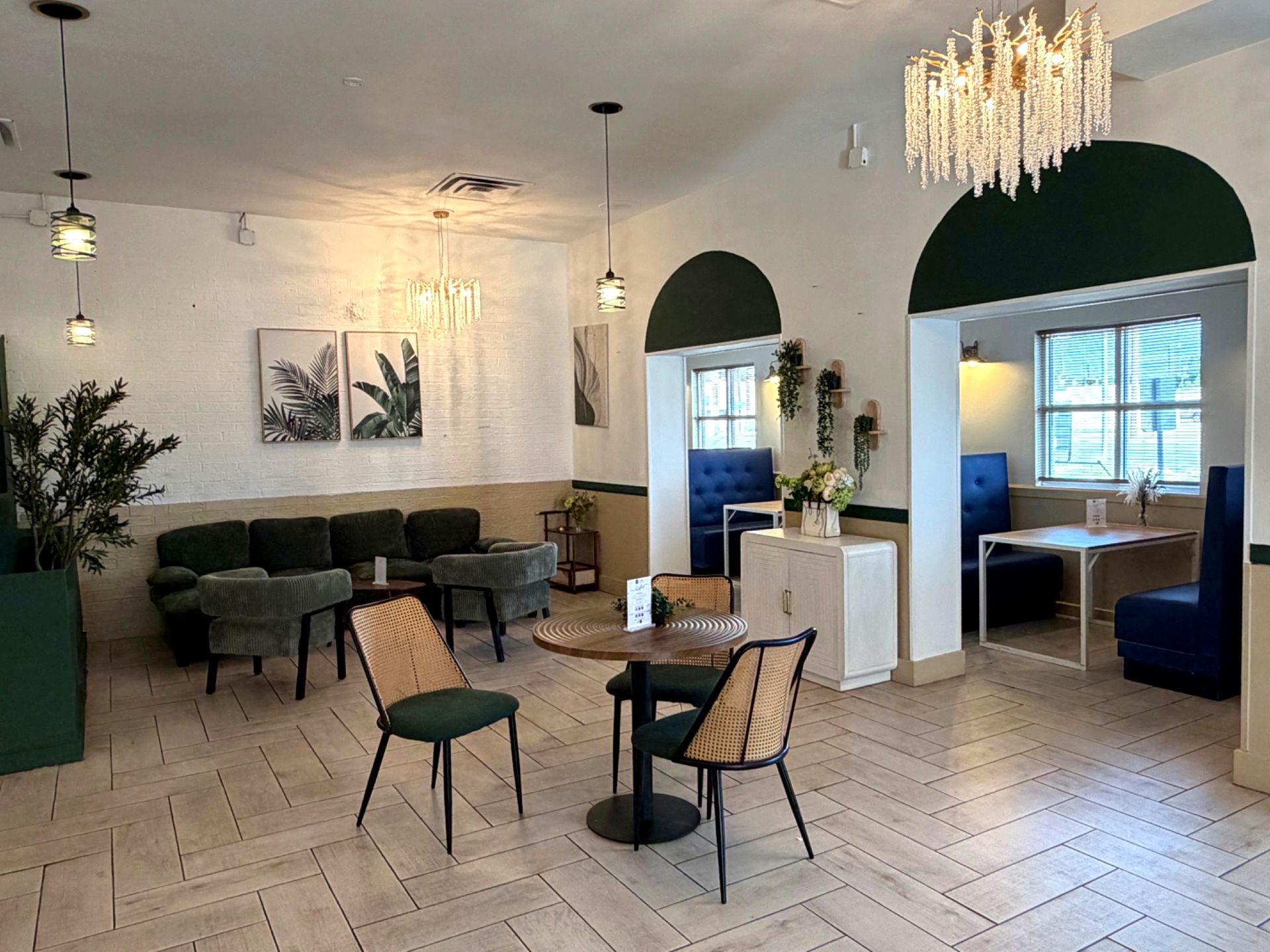 Modern lounge with green chairs, tables, sofas, and arched doorways in a bright white interior