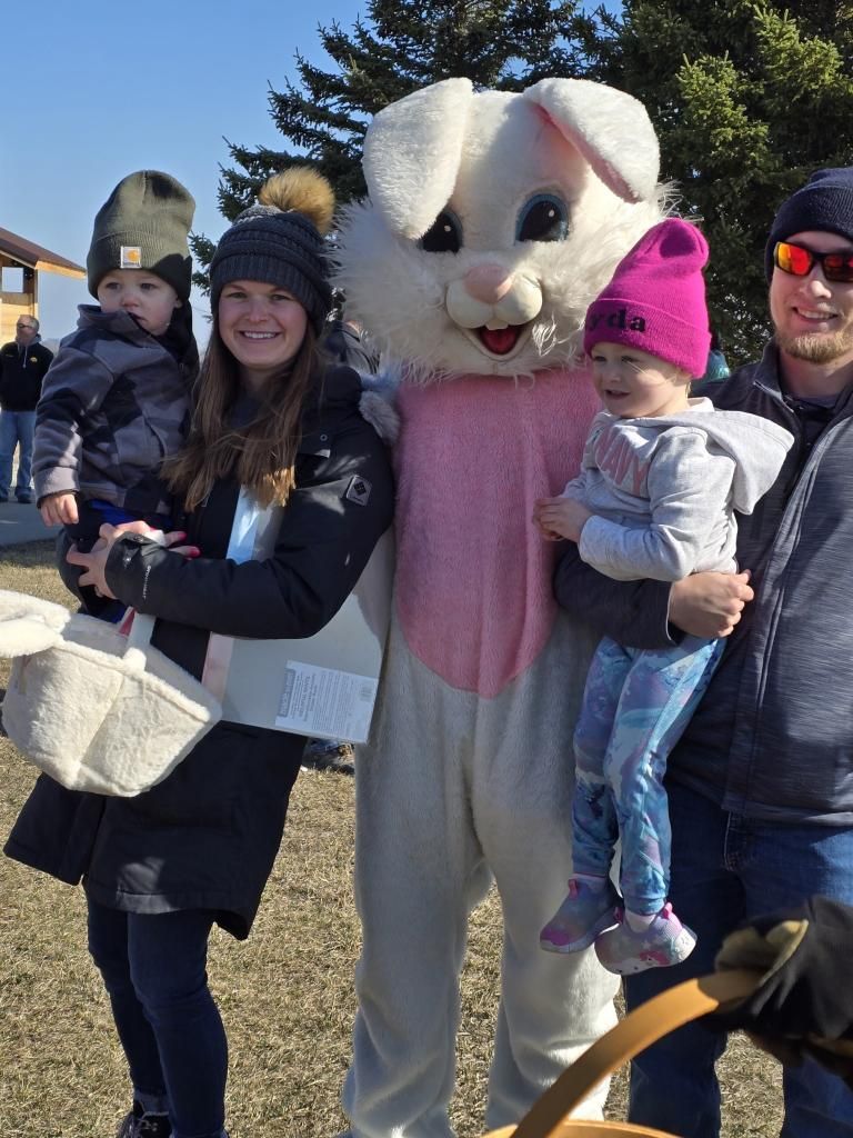 Family of four holding hands, playing in sunny backyard.