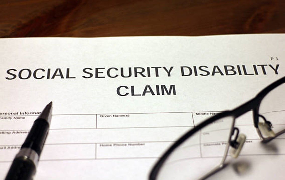 A pen and glasses sit on top of a social security disability claim form.