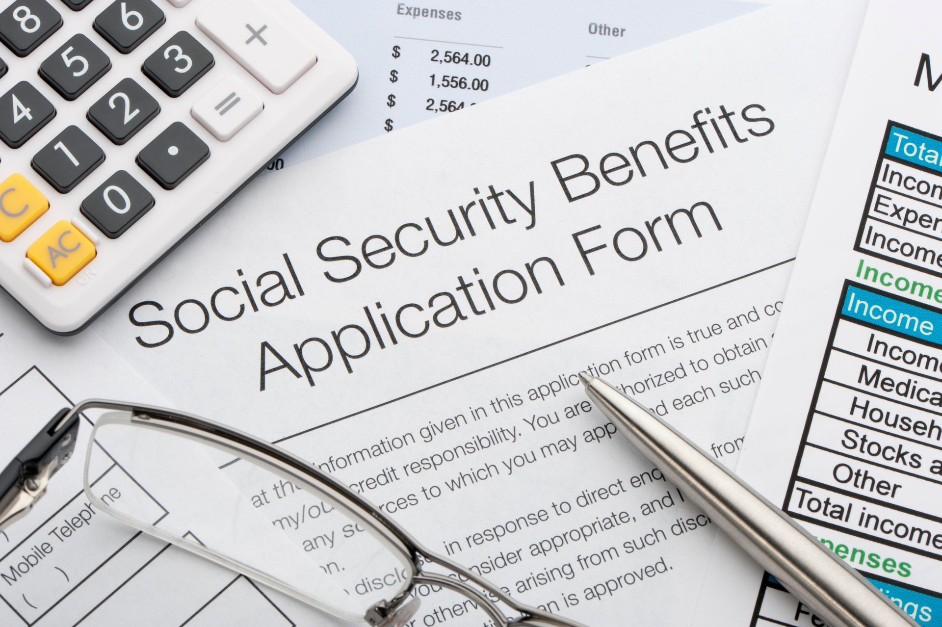 A Calculator Is Sitting on Top of A Social Security Benefits Application Form