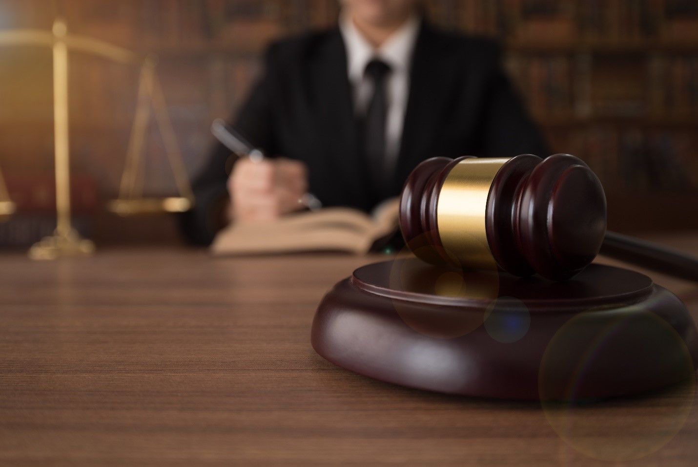 A judge is sitting at a table with a book and a gavel.