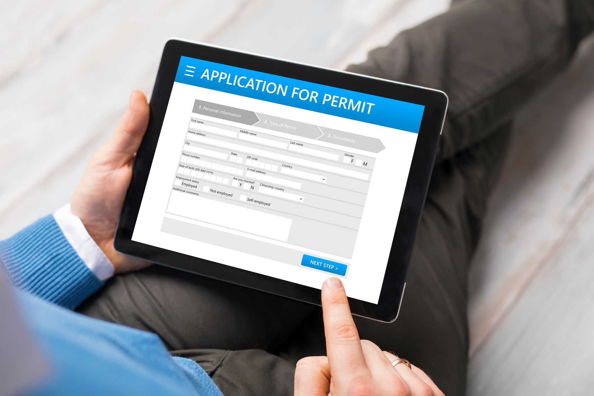 Person using tablet to complete online permit application form.