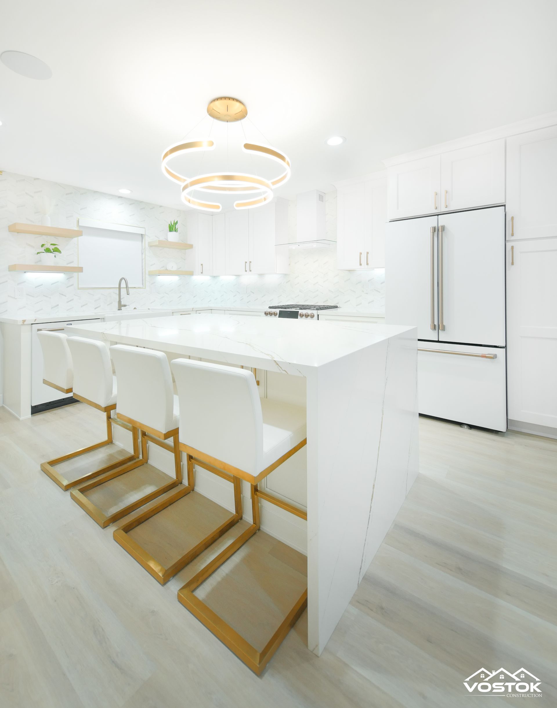 A kitchen with white cabinets and gold chairs