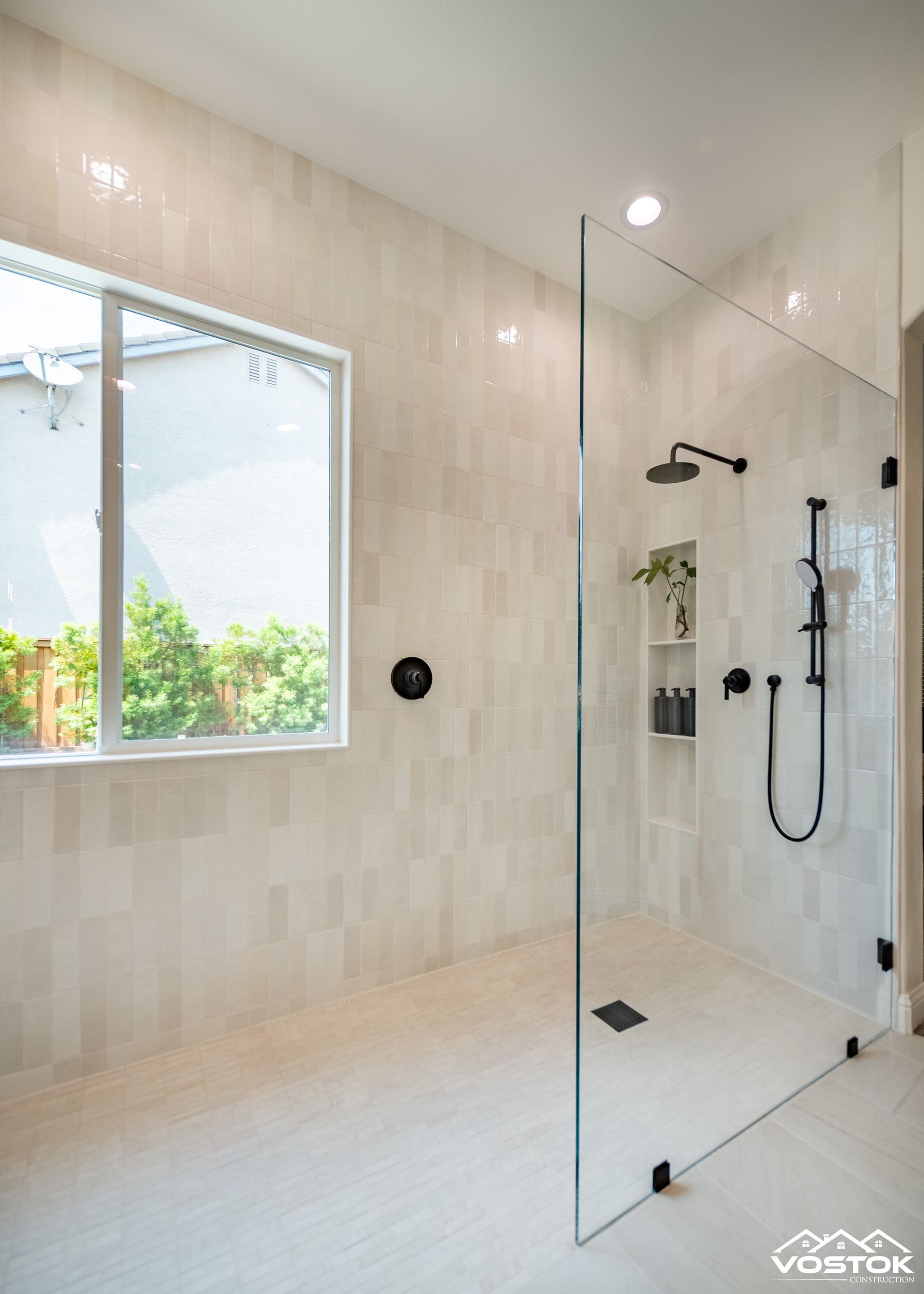 A bathroom with a walk in shower and a window.