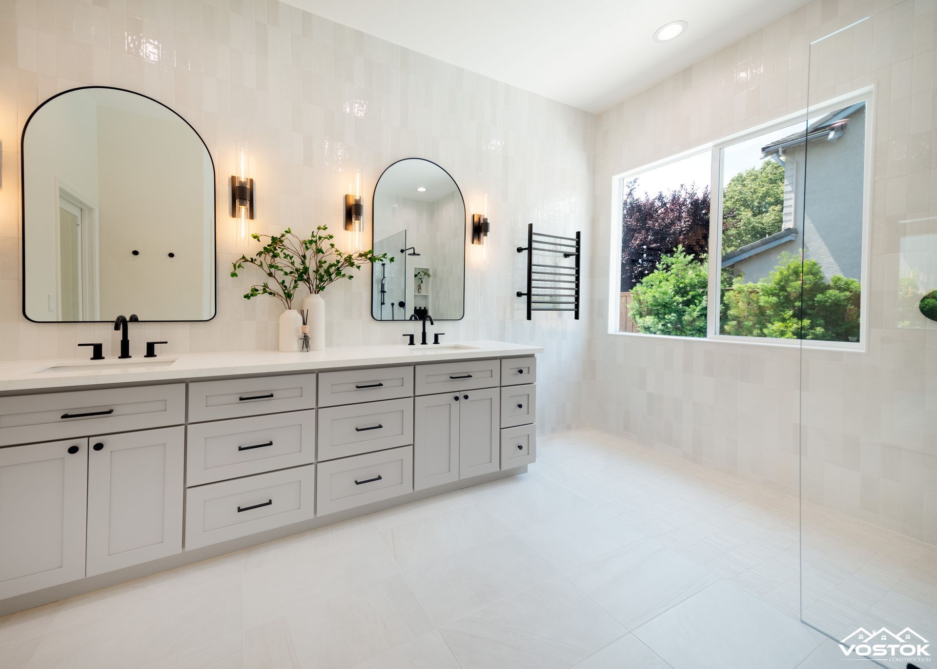 A bathroom with two sinks , two mirrors and two windows.