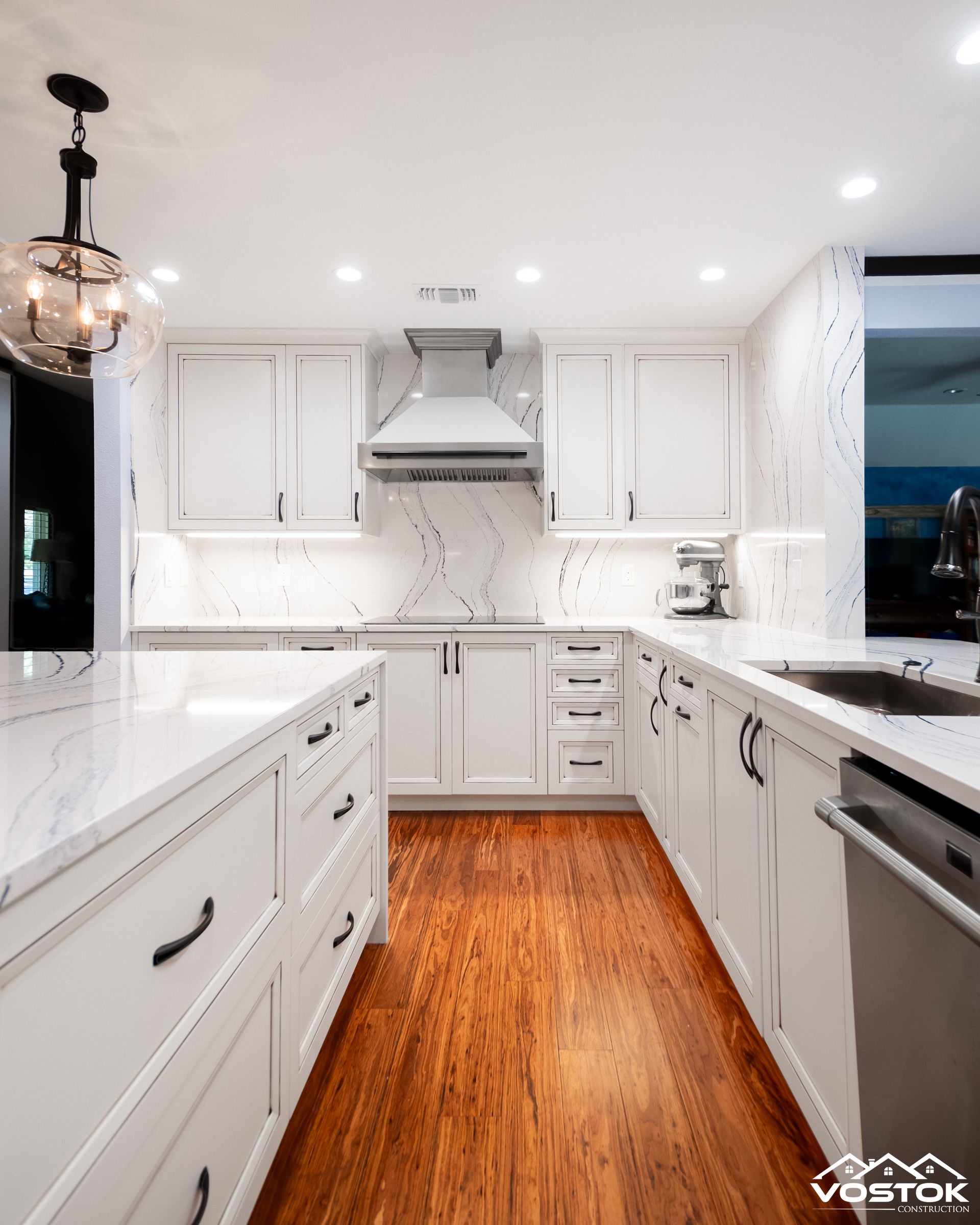 A kitchen with white cabinets and hardwood floors.