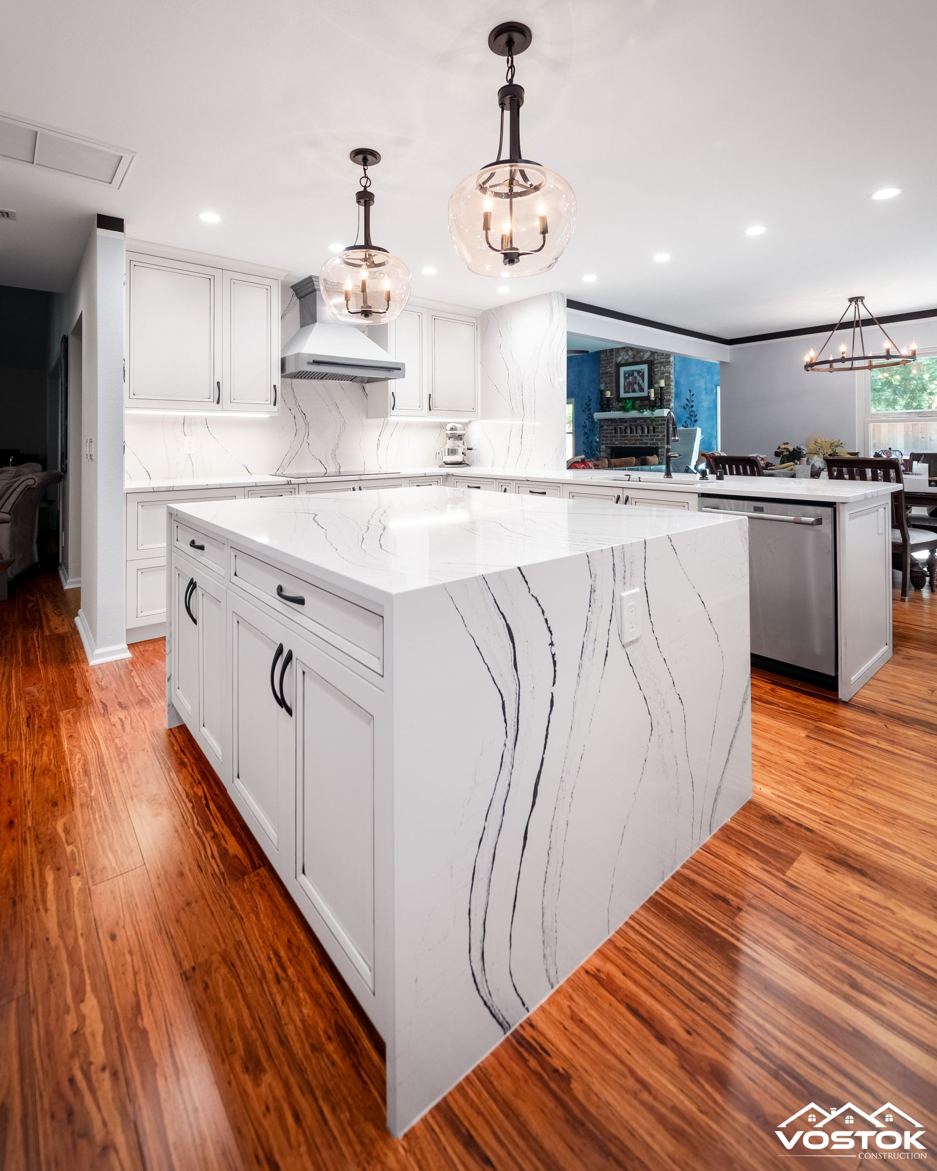 A kitchen with white cabinets and a large island in the middle.