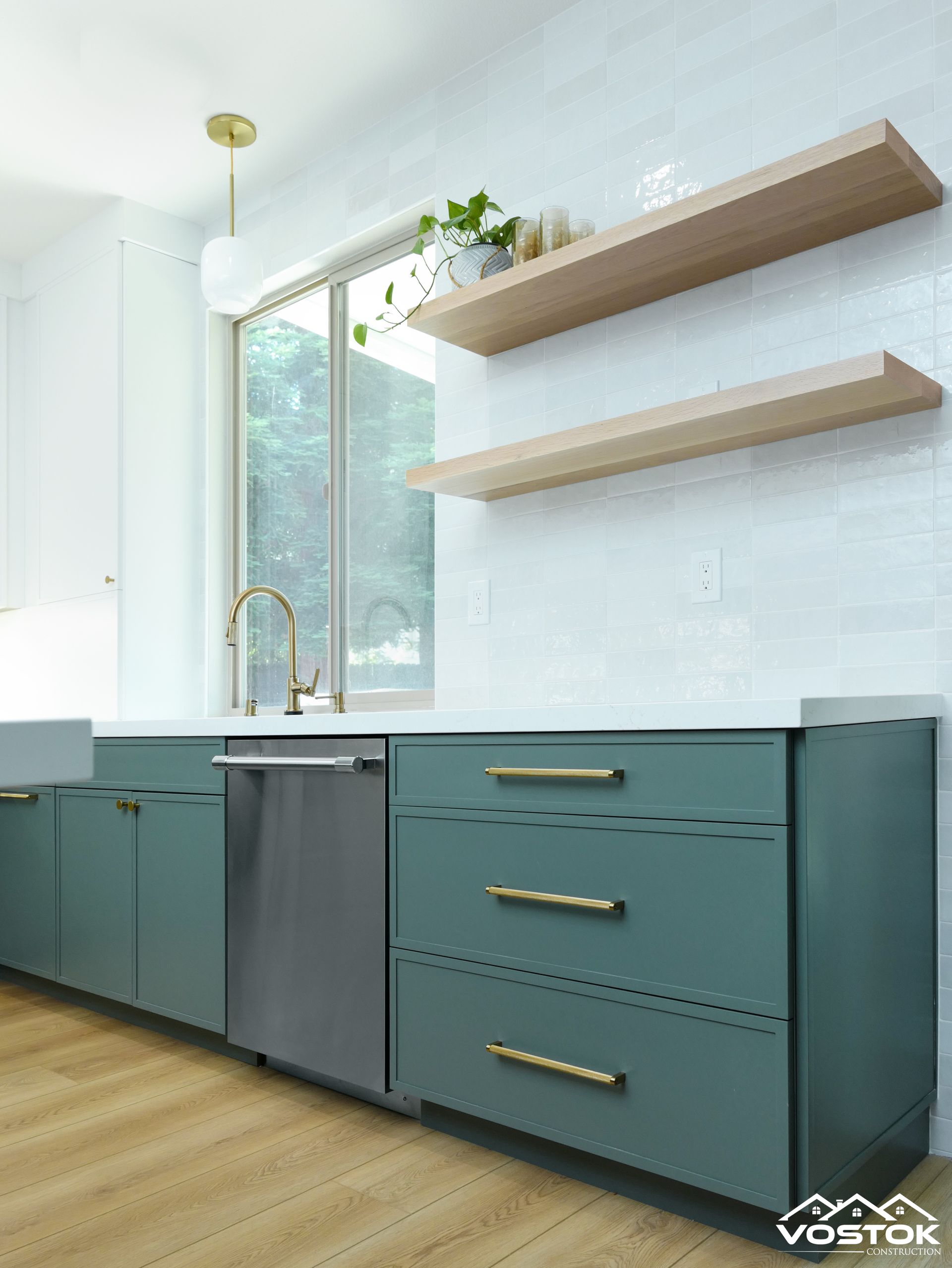 A kitchen with green cabinets , stainless steel appliances , and wooden shelves.