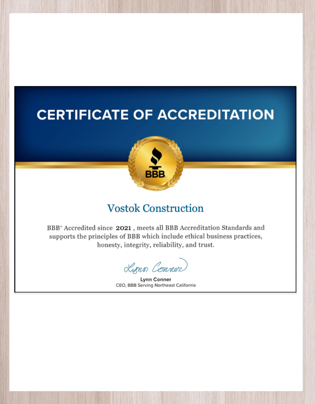 A certificate of accreditation is sitting on a wooden table.