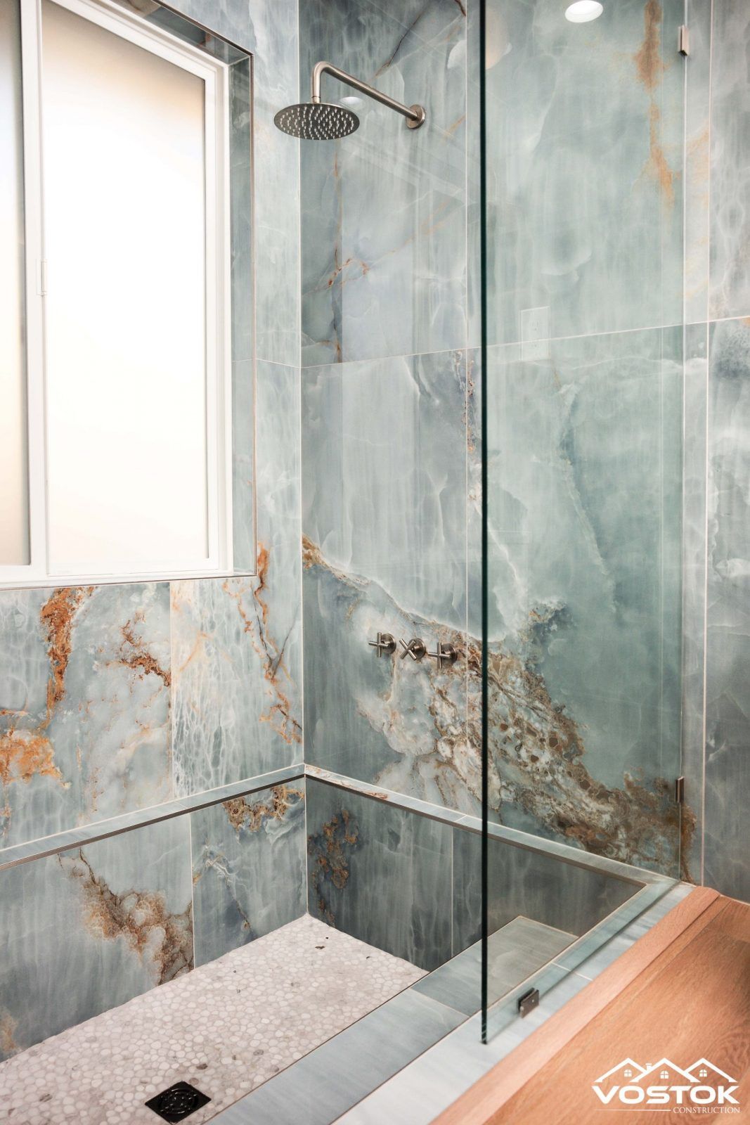 A bathroom with a walk in shower and a window.