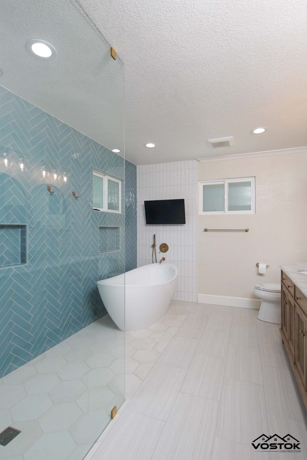 A bathroom with a bathtub , toilet , shower and television.