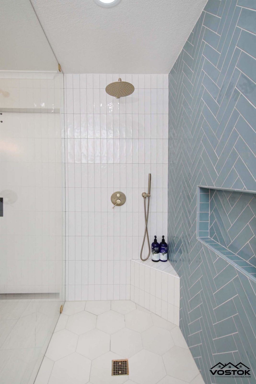A bathroom with blue and white tiles and a walk in shower.