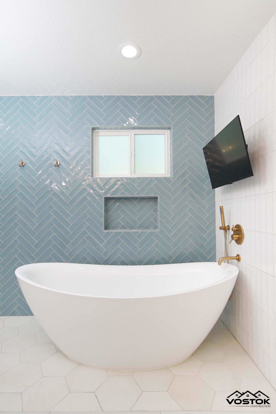 A bathroom with a bathtub and a television on the wall.