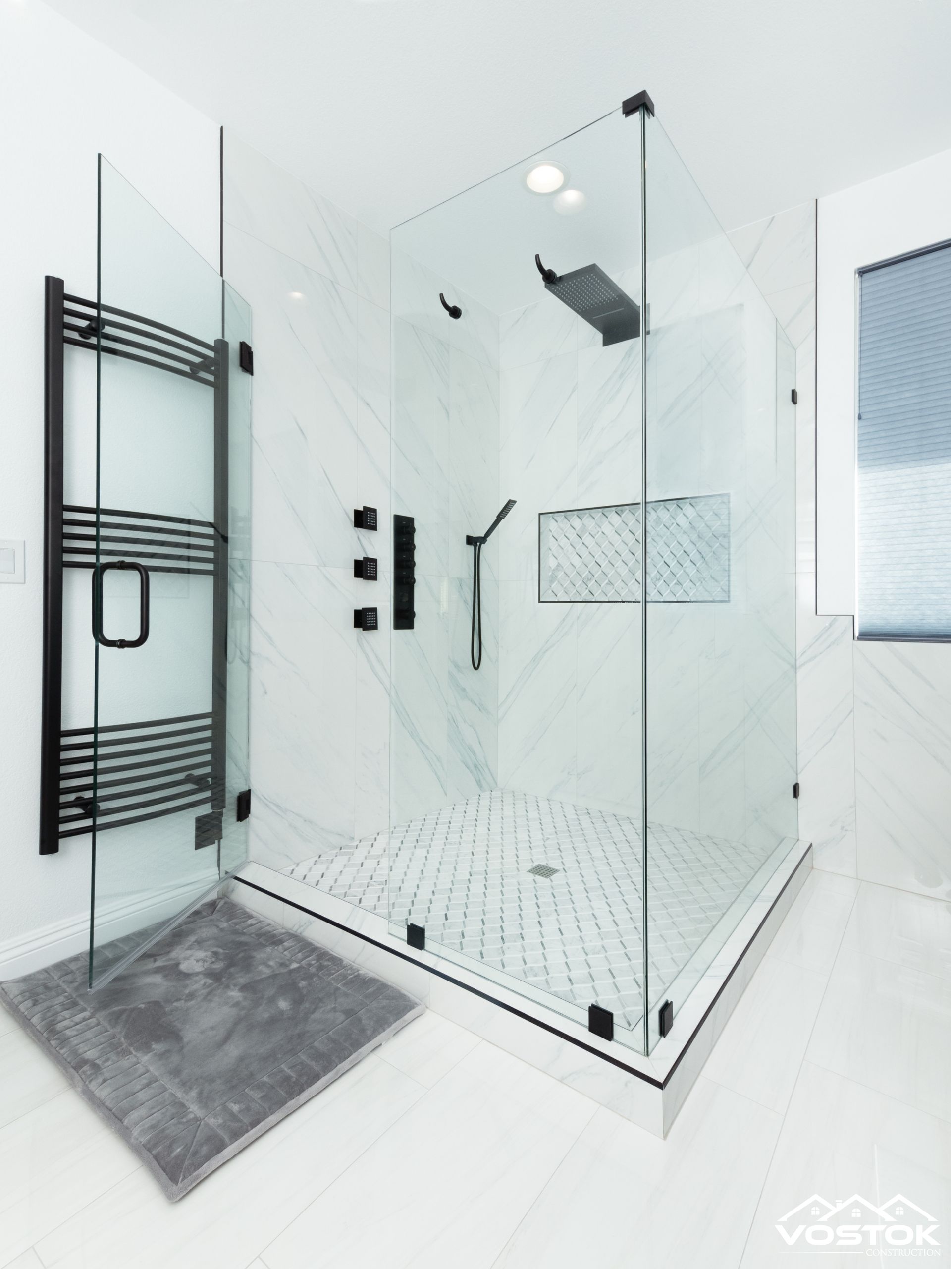 A bathroom with a walk in shower and a towel rack