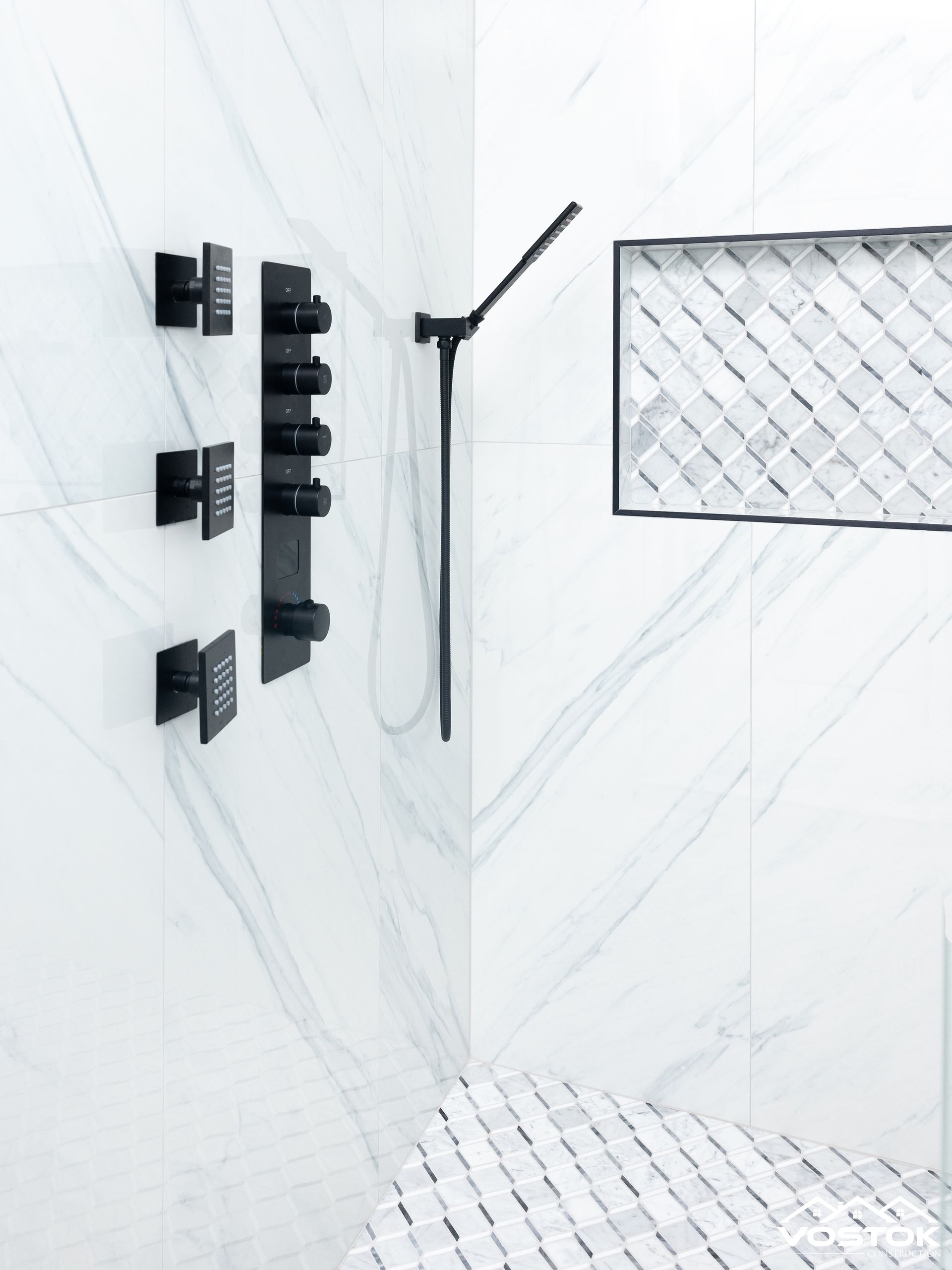 A bathroom with white tiles and black shower heads
