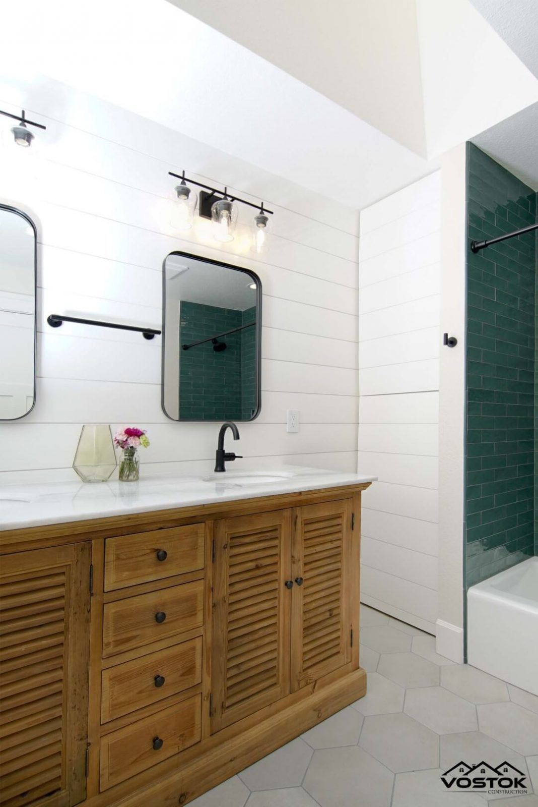 A bathroom with two sinks , two mirrors and a shower.