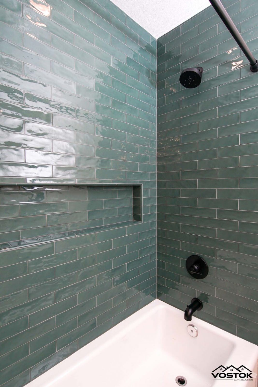 A bathroom with green tiles and a bathtub.