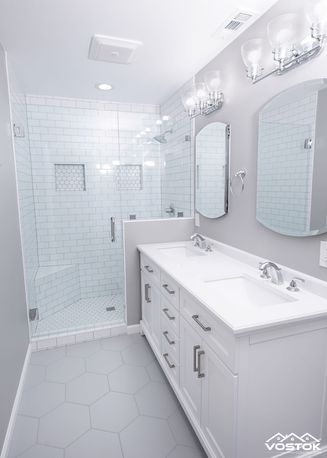 A bathroom with two sinks , a shower , and a mirror.
