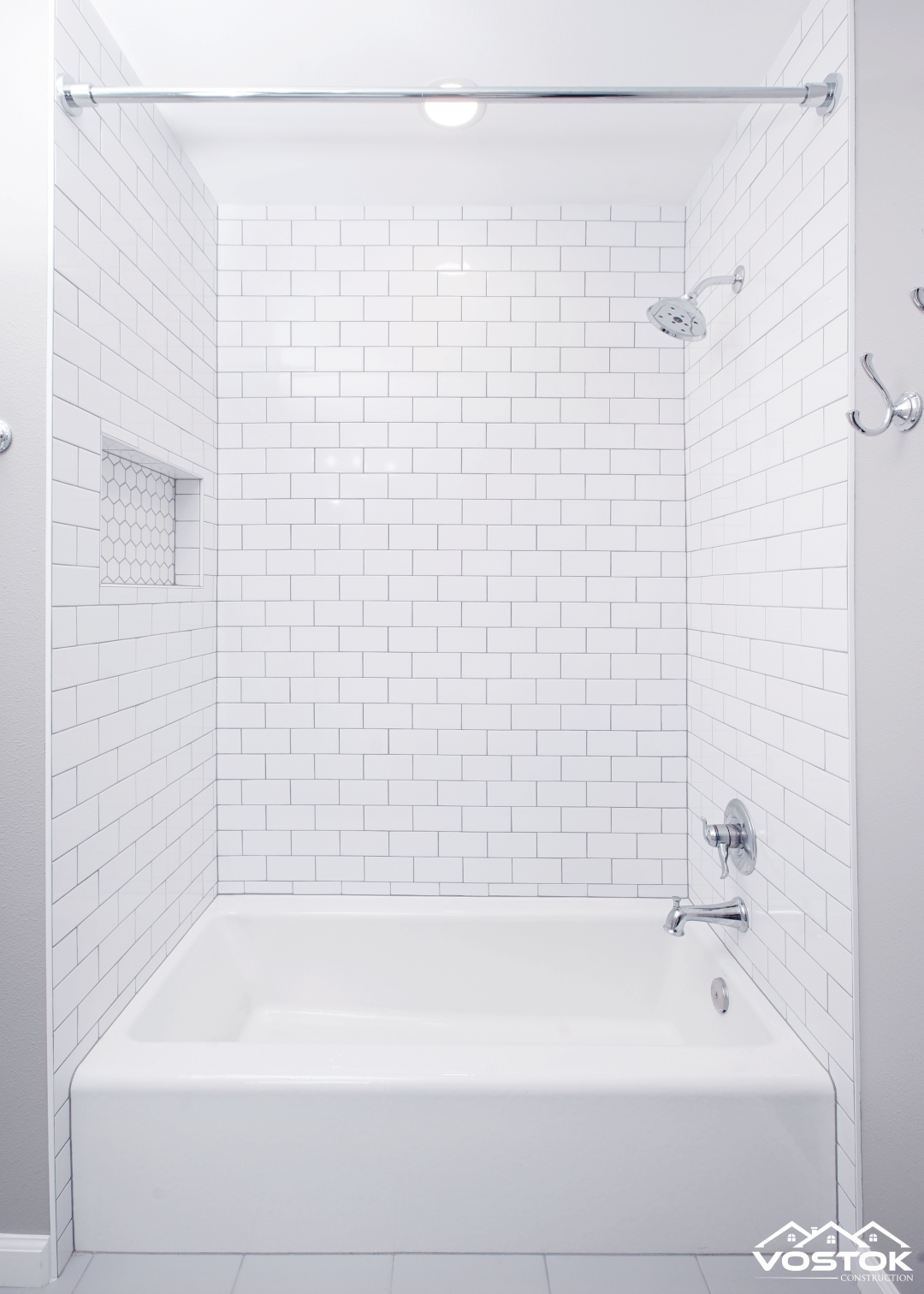 A bathroom with white tiles and a bathtub.